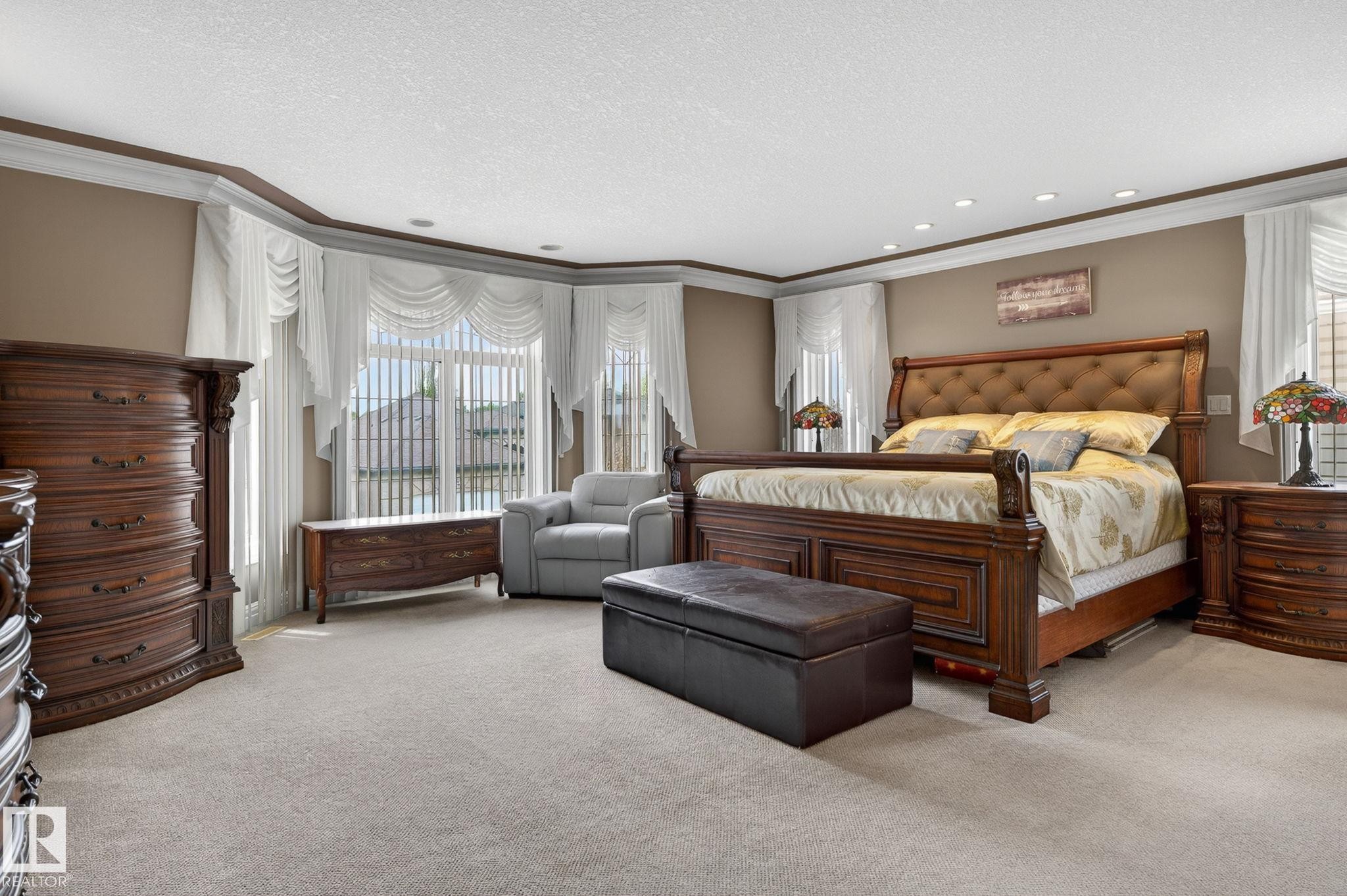 Spacious living area featuring high ceilings, a grand arched entryway with columns, and a curved staircase with wrought iron balusters - 1508 Palmer Close, Edmonton, AB
