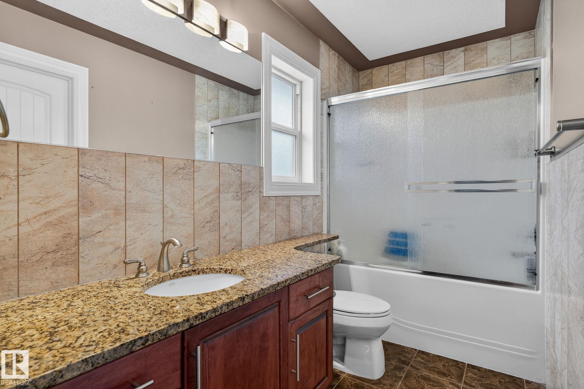 Expansive kitchen featuring wood cabinetry, granite countertops, and a black tile backsplash - 1508 Palmer Close, Edmonton, AB