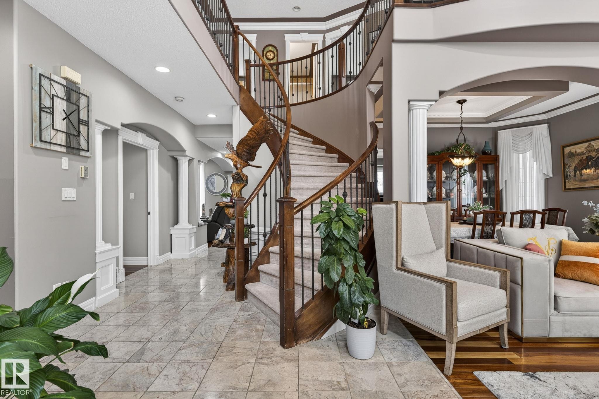 Brick exterior with stacked stone accents, arched double entry doors, a white garage door, concrete stairs, and a mature evergreen shrub - 1508 Palmer Close, Edmonton, AB