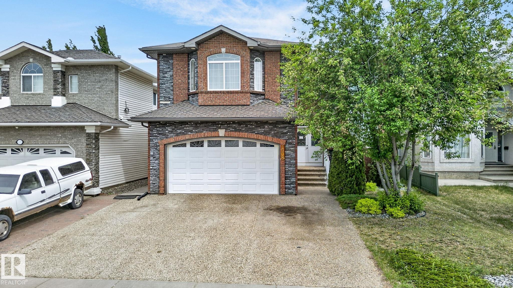 Carpeted bedroom featuring a double-door bi-fold closet, two windows with exterior views, and a ceiling-mounted light fixture - 1508 Palmer Close, Edmonton, AB