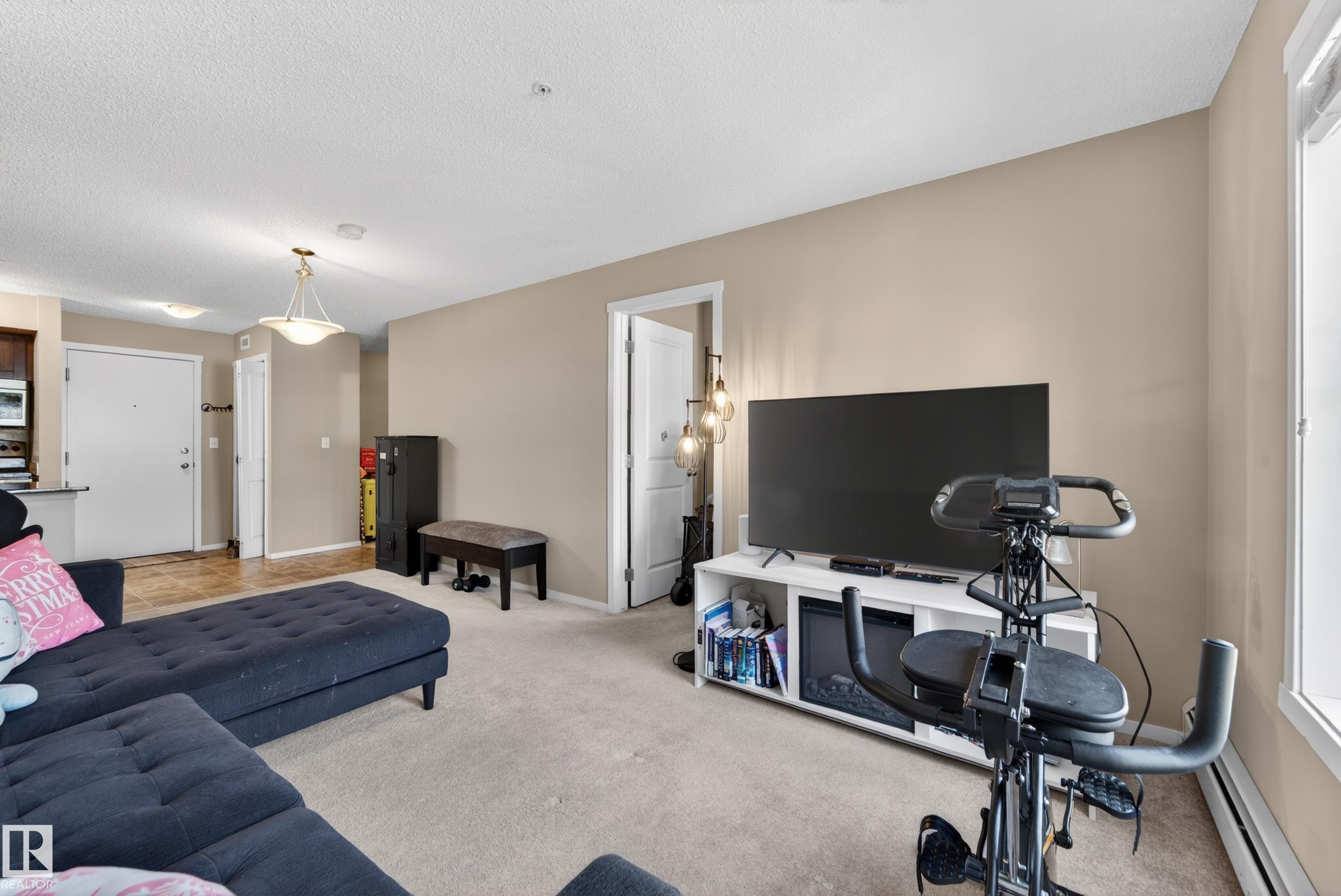 Carpeted living area featuring light beige wall tones and white trim - 225 1510 Watt Drive, Edmonton, AB - Indoor Photo Showing Living Room