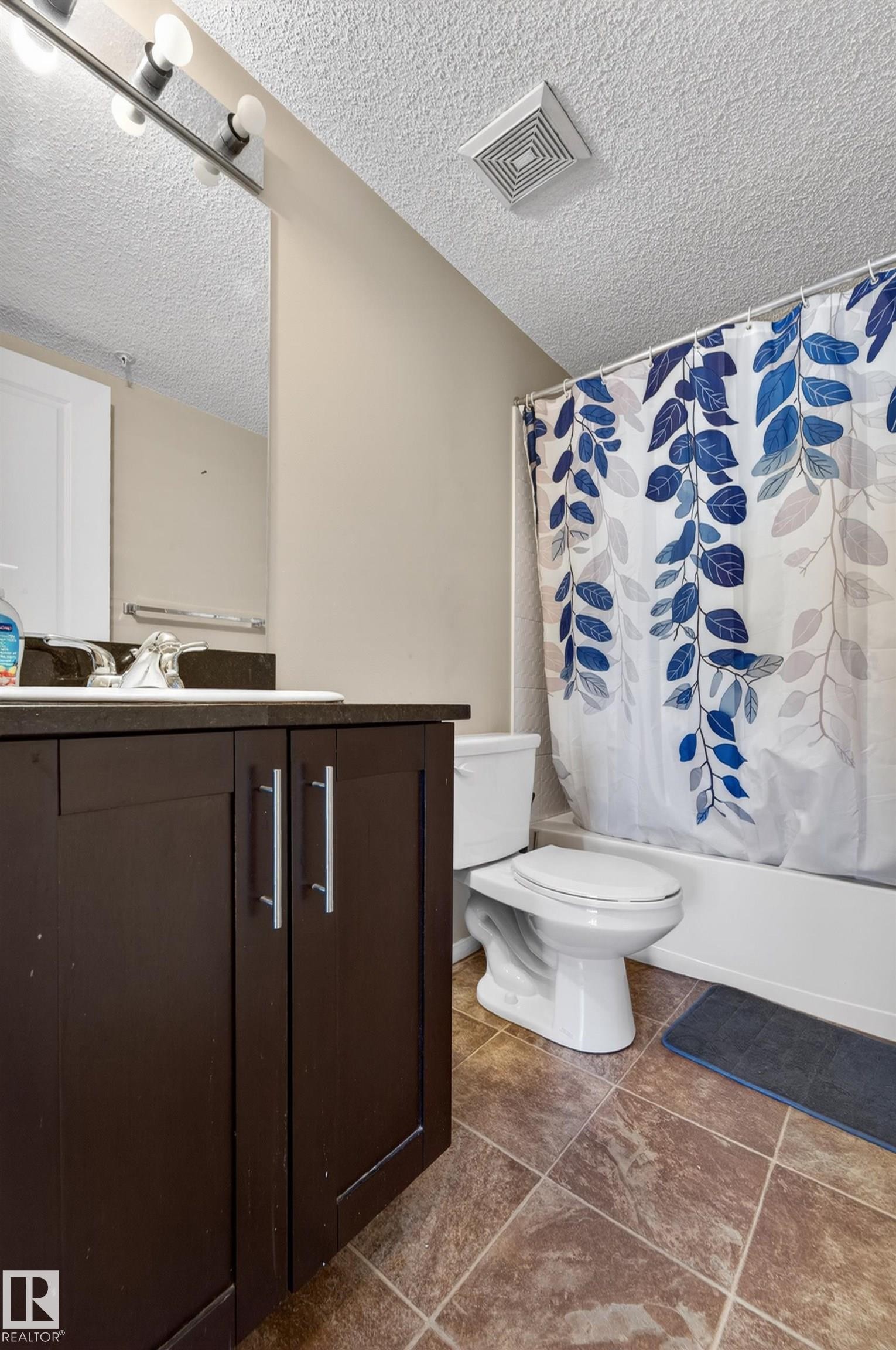 Bathroom featuring a dark wood-finish vanity with silver-tone hardware, a rectangular sink, and a framed mirror - 225 1510 Watt Drive, Edmonton, AB - Indoor Photo Showing Bathroom