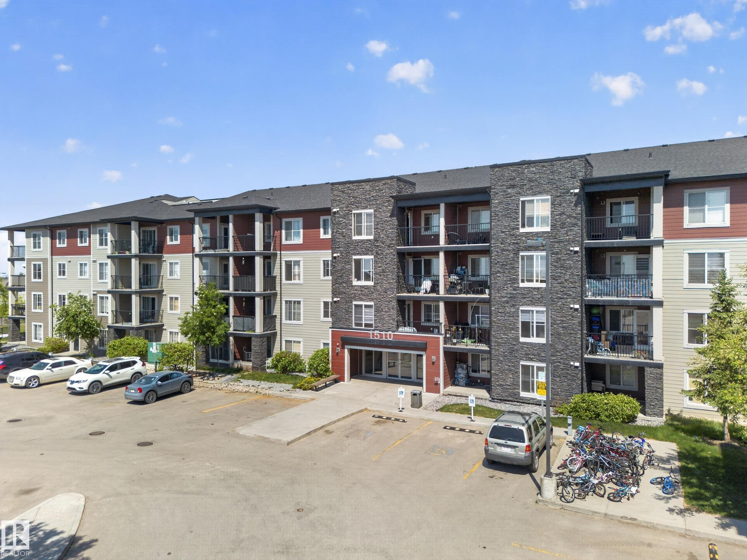 Multi-story building featuring a stone and siding facade, private balconies, a designated parking area, and a prominent main entrance - 225 1510 Watt Drive, Edmonton, AB - Outdoor With Facade