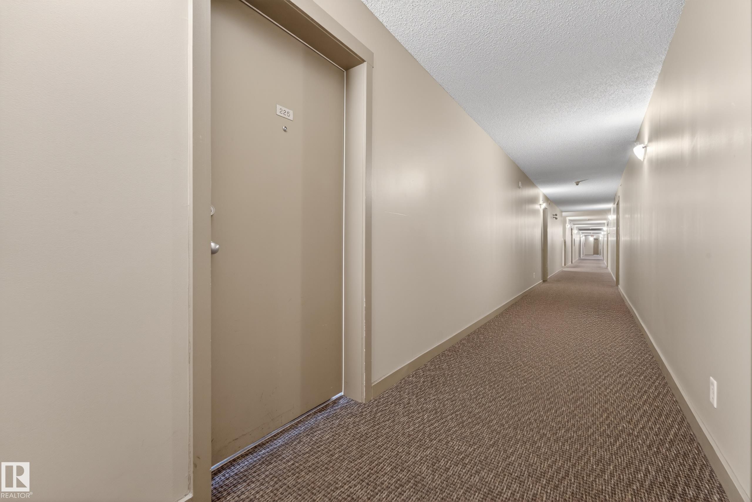 Long interior corridor with textured carpet flooring and light neutral wall paint - 225 1510 Watt Drive, Edmonton, AB - Indoor Photo Showing Other Room