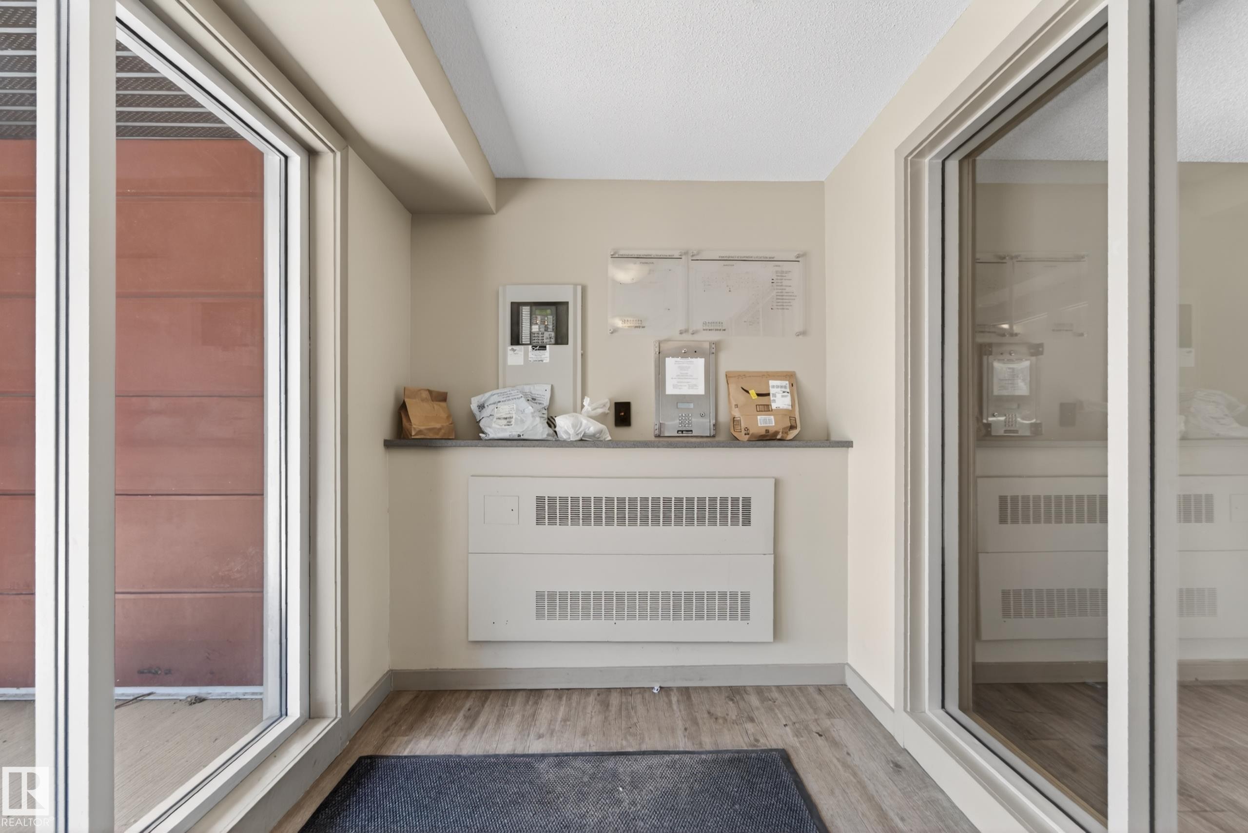 Entry area featuring wood-finish flooring, light neutral wall paint, and a built-in counter - 225 1510 Watt Drive, Edmonton, AB - Indoor Photo Showing Other Room