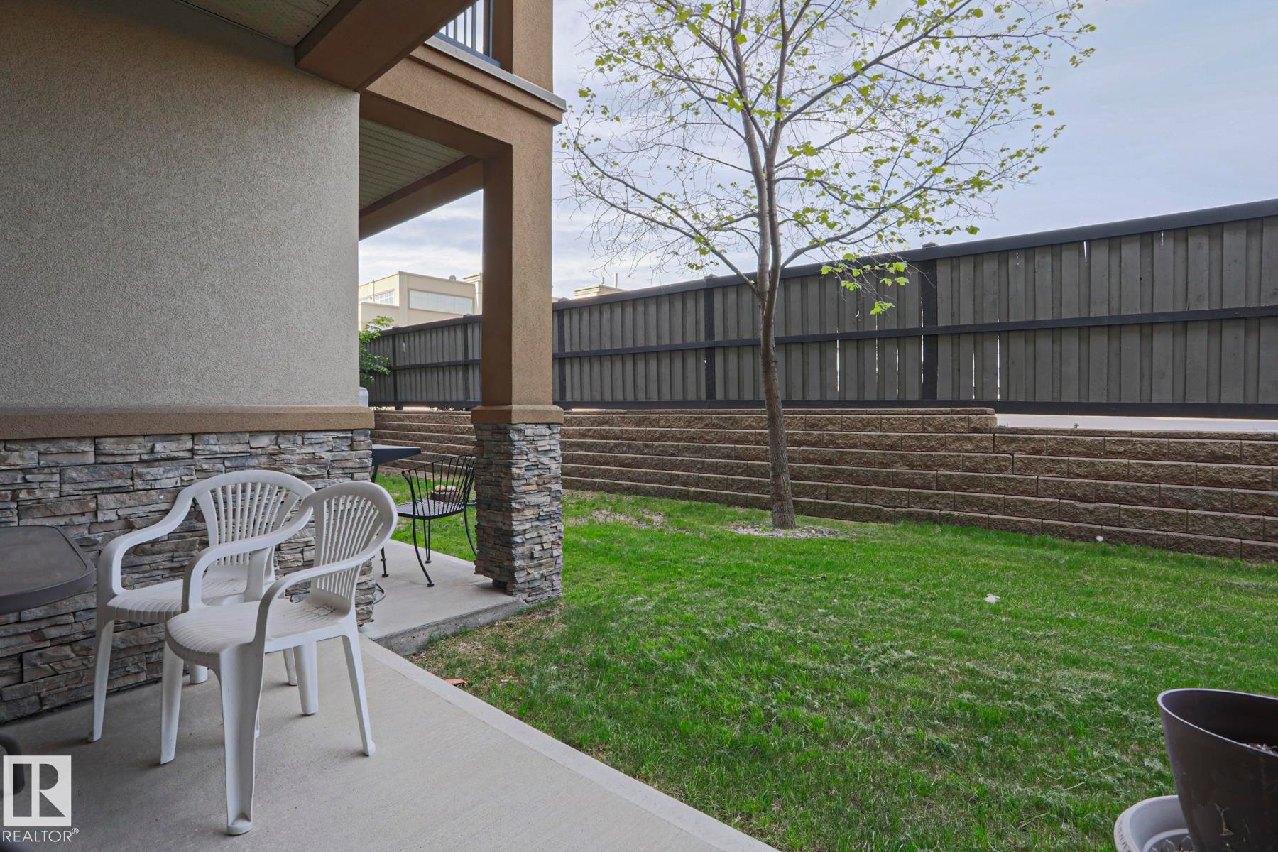 Covered patio area with concrete flooring, stone veneer accents, and stucco siding - 117 160 Magrath Road, Edmonton, AB - Outdoor With Deck Patio Veranda