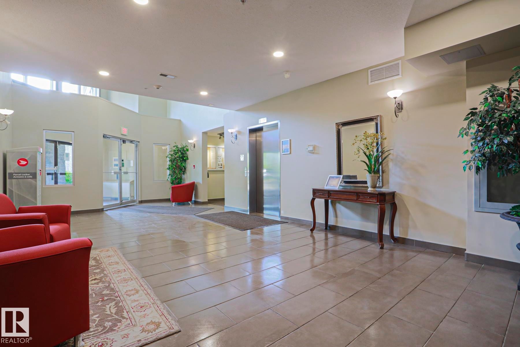 Lobby area featuring large format tile flooring, recessed lighting, and a stainless steel elevator - 117 160 Magrath Road, Edmonton, AB - Indoor