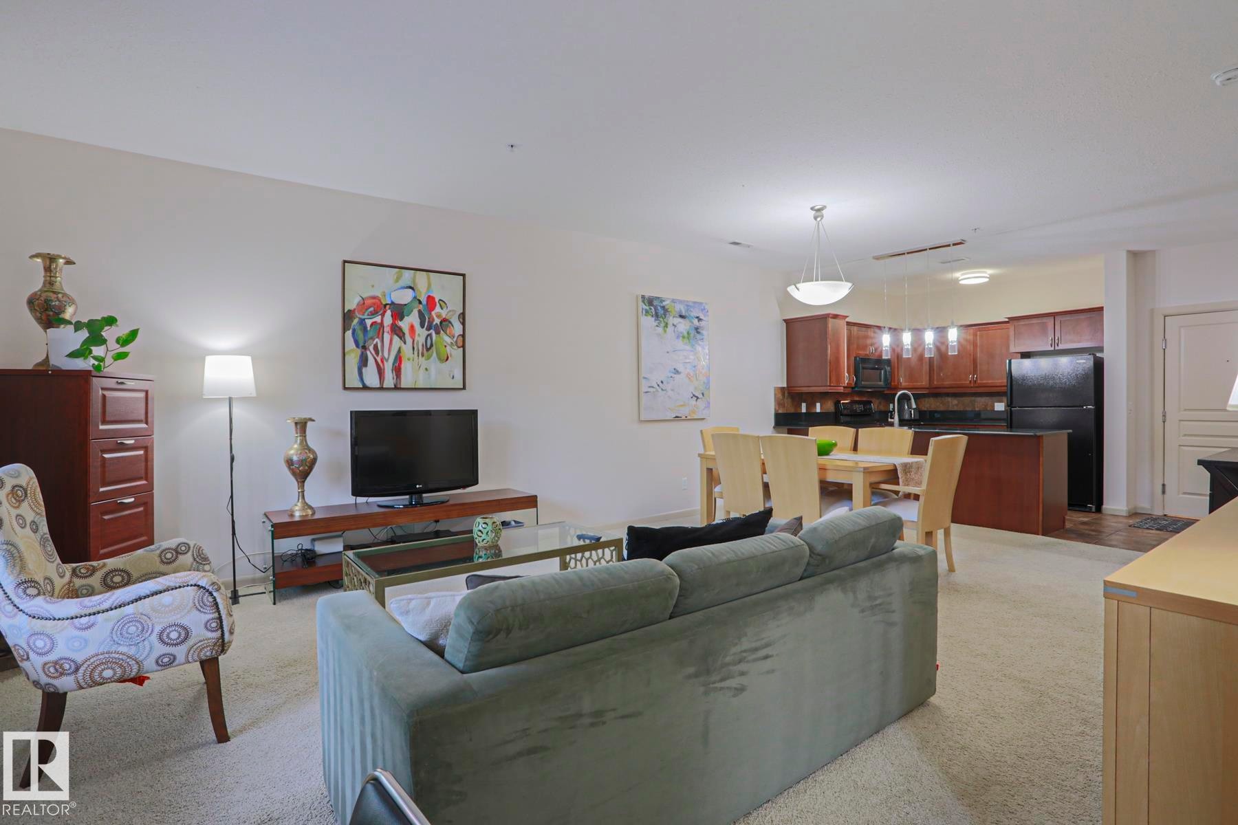 Open-concept living area with carpeting, recessed lighting, and a chandelier - 117 160 Magrath Road, Edmonton, AB - Indoor Photo Showing Living Room