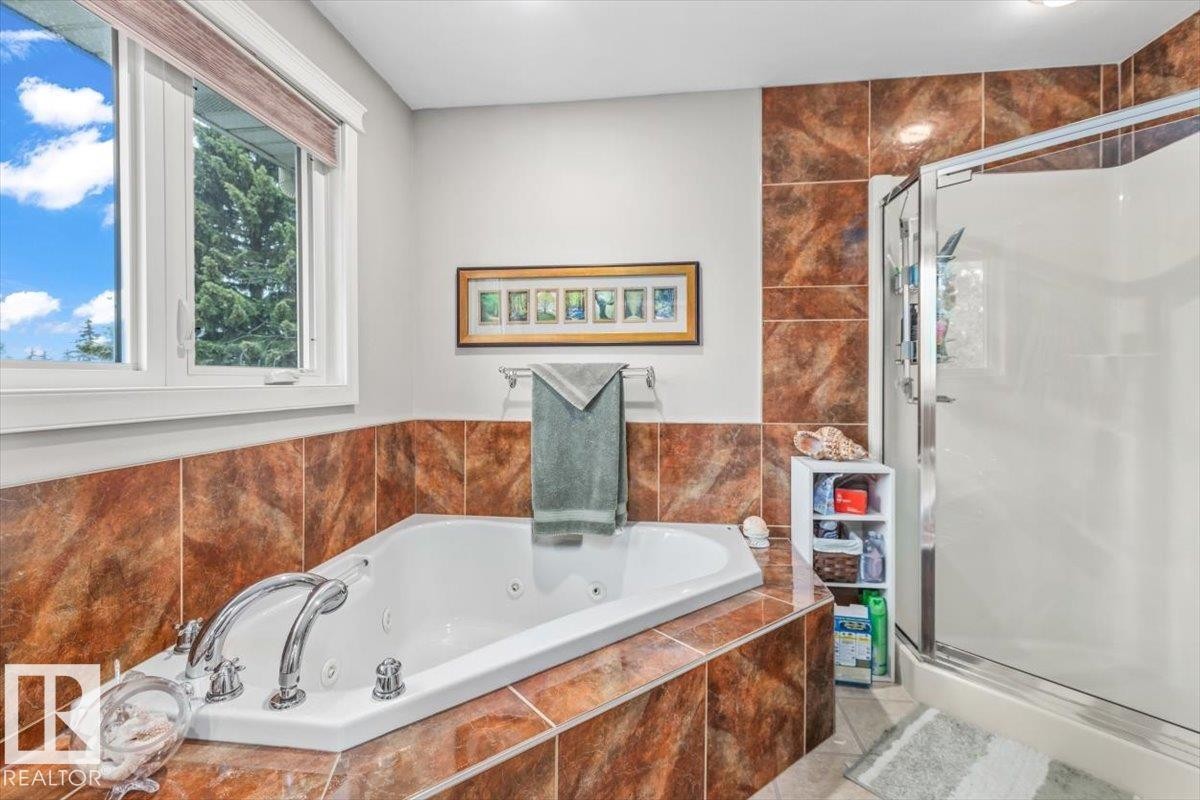 Bathroom featuring a built-in jetted tub, a separate shower enclosure with a glass door, and extensive brown-toned wall and tub surround tiling - 6720 29 Avenue, Edmonton, AB