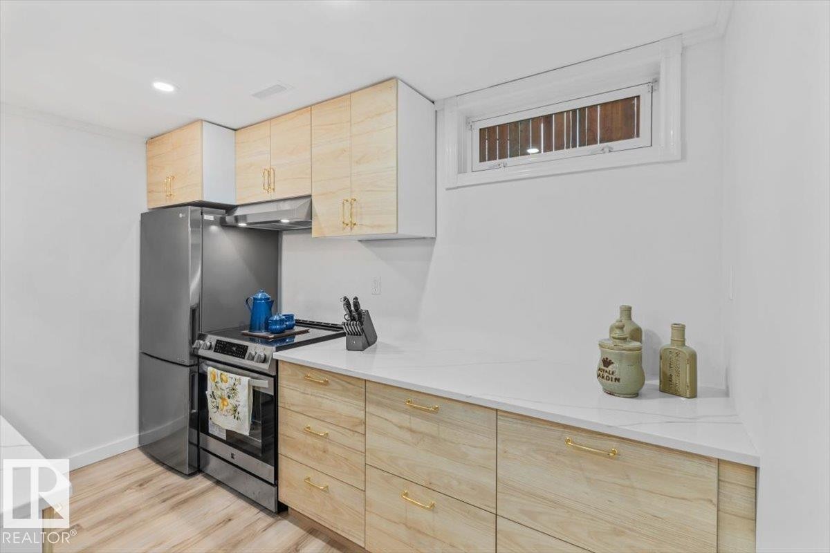 Kitchen featuring light wood-finish cabinetry, quartz-style countertops, stainless steel appliances, and recessed lighting - 6720 29 Avenue, Edmonton, AB