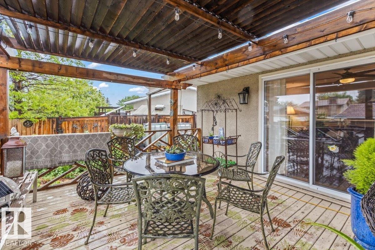 Covered outdoor deck featuring a wood-finish pergola with string lighting and a sliding glass door entry - 6720 29 Avenue, Edmonton, AB