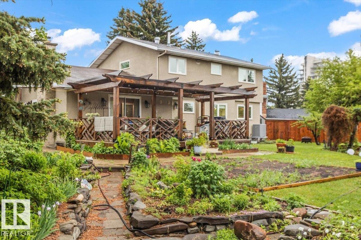 Rear exterior featuring a stucco facade, multiple windows, and a wood-slat pergola over a deck with decorative railing - 6720 29 Avenue, Edmonton, AB