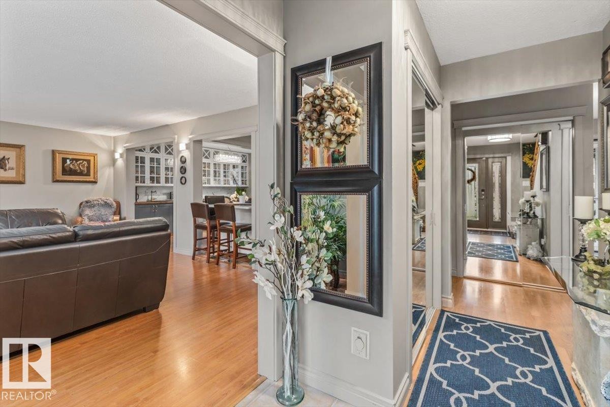 Open-concept living area featuring wood-finish flooring, a kitchen with white cabinetry, a breakfast bar, and a clear sightline to the entryway with a double door - 6720 29 Avenue, Edmonton, AB