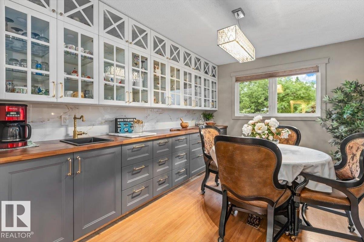 Kitchen and dining area featuring two-tone cabinetry, wood-finish countertops, and a white marble-patterned backsplash - 6720 29 Avenue, Edmonton, AB