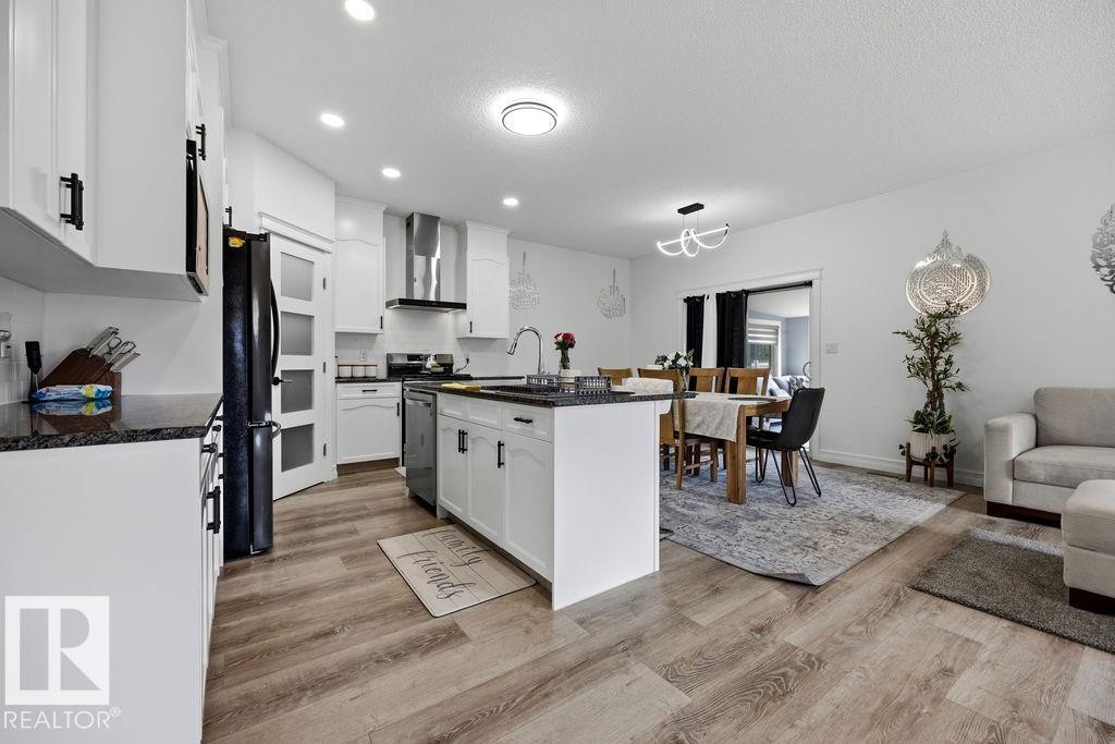Contemporary kitchen featuring white cabinetry, dark countertops, wood-finish flooring, a stainless steel range hood, and recessed lighting - 13703 166 Avenue Nw, Edmonton, AB - Indoor Photo Showing Kitchen With Upgraded Kitchen