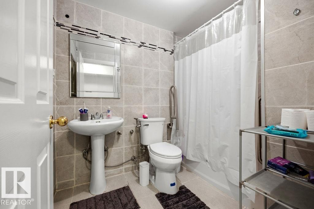 Full bathroom featuring light-toned square wall tiles with a decorative accent band - 13703 166 Avenue Nw, Edmonton, AB - Indoor Photo Showing Bathroom