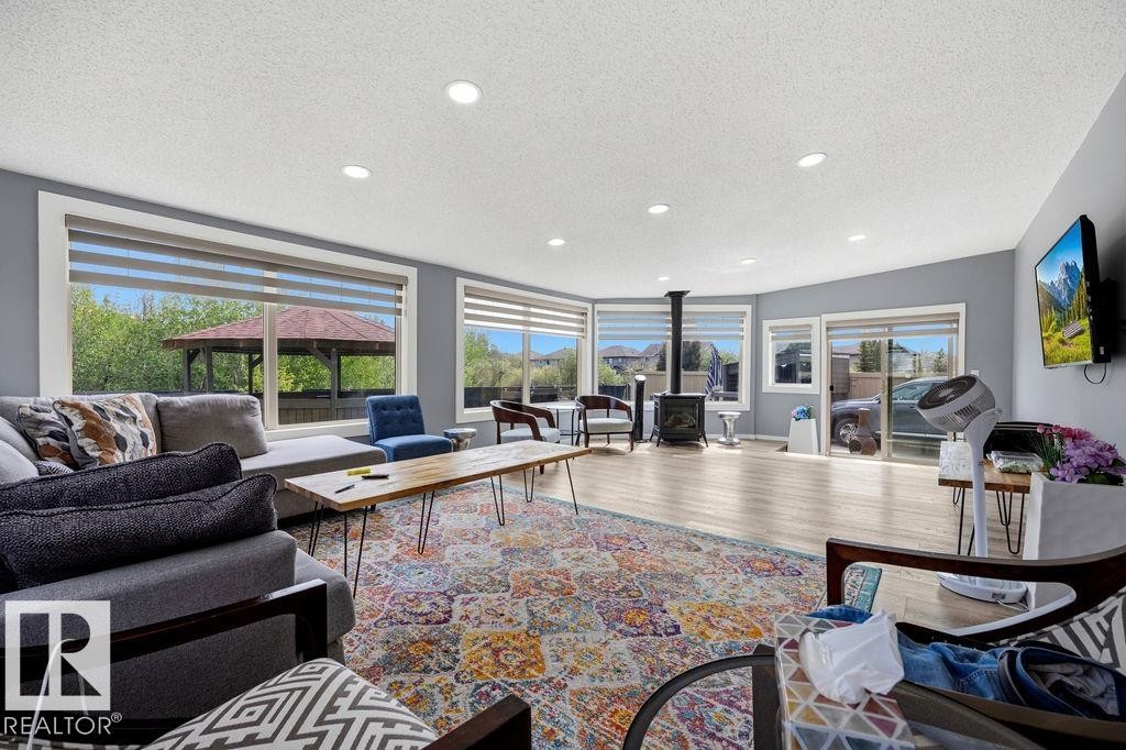 Spacious living area featuring wood-finish flooring, recessed lighting, and a freestanding stove - 13703 166 Avenue Nw, Edmonton, AB - Indoor Photo Showing Living Room