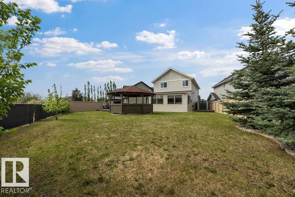 Expansive backyard featuring a central gazebo with a shingled roof, a manicured lawn, and mature perimeter trees - 13703 166 Avenue Nw, Edmonton, AB - Outdoor