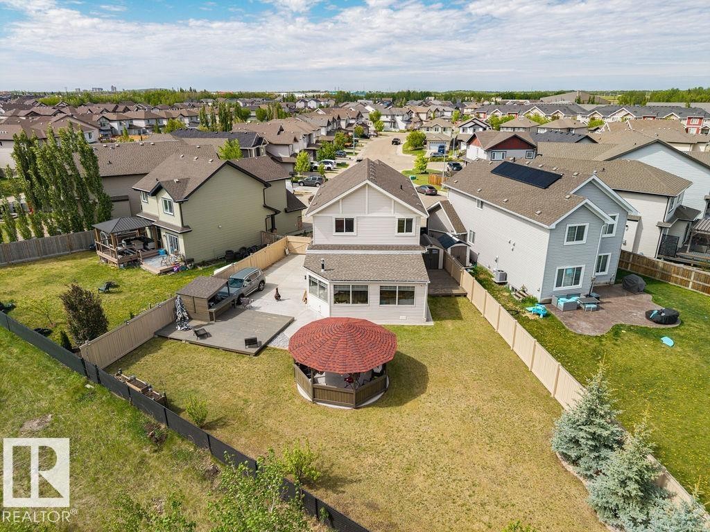 Expansive backyard featuring a red-roofed gazebo, a concrete patio area, and a large grassy lawn - 13703 166 Avenue Nw, Edmonton, AB - Outdoor With View