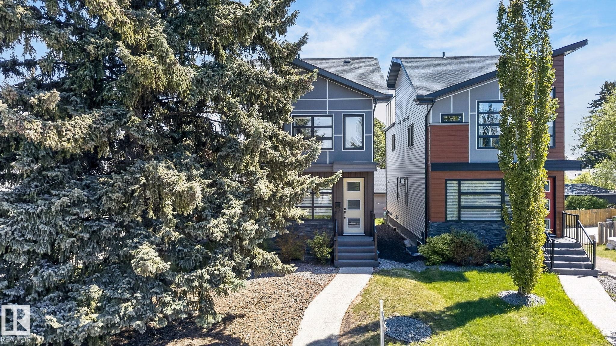 Contemporary exterior featuring a distinctive sloped roofline, dark-framed windows, and a mix of grey siding with brown accent panels - 8809 148 Street, Edmonton, AB - Outdoor With Facade