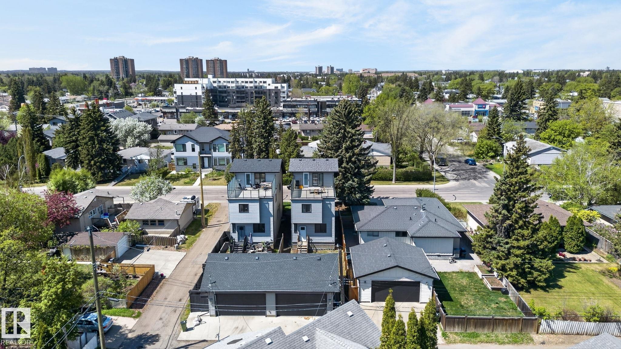 Contemporary duplex featuring light blue siding with dark trim, multiple balconies, and a rooftop patio - 8809 148 Street, Edmonton, AB - Outdoor With View