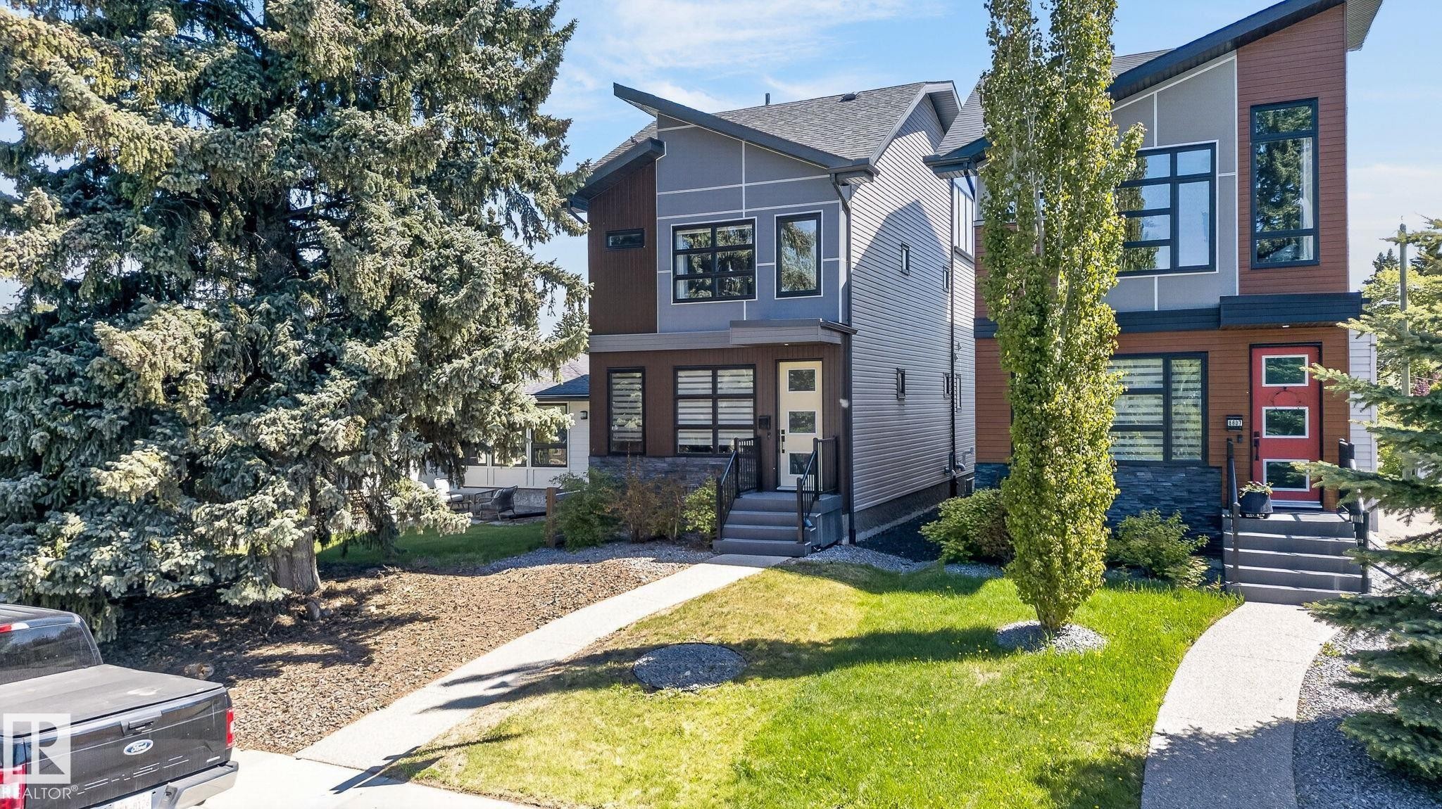 Modern architectural design featuring multi-toned siding, a distinct roofline, numerous windows with dark frames, and a front walkway leading to the entrance - 8809 148 Street, Edmonton, AB - Outdoor With Facade
