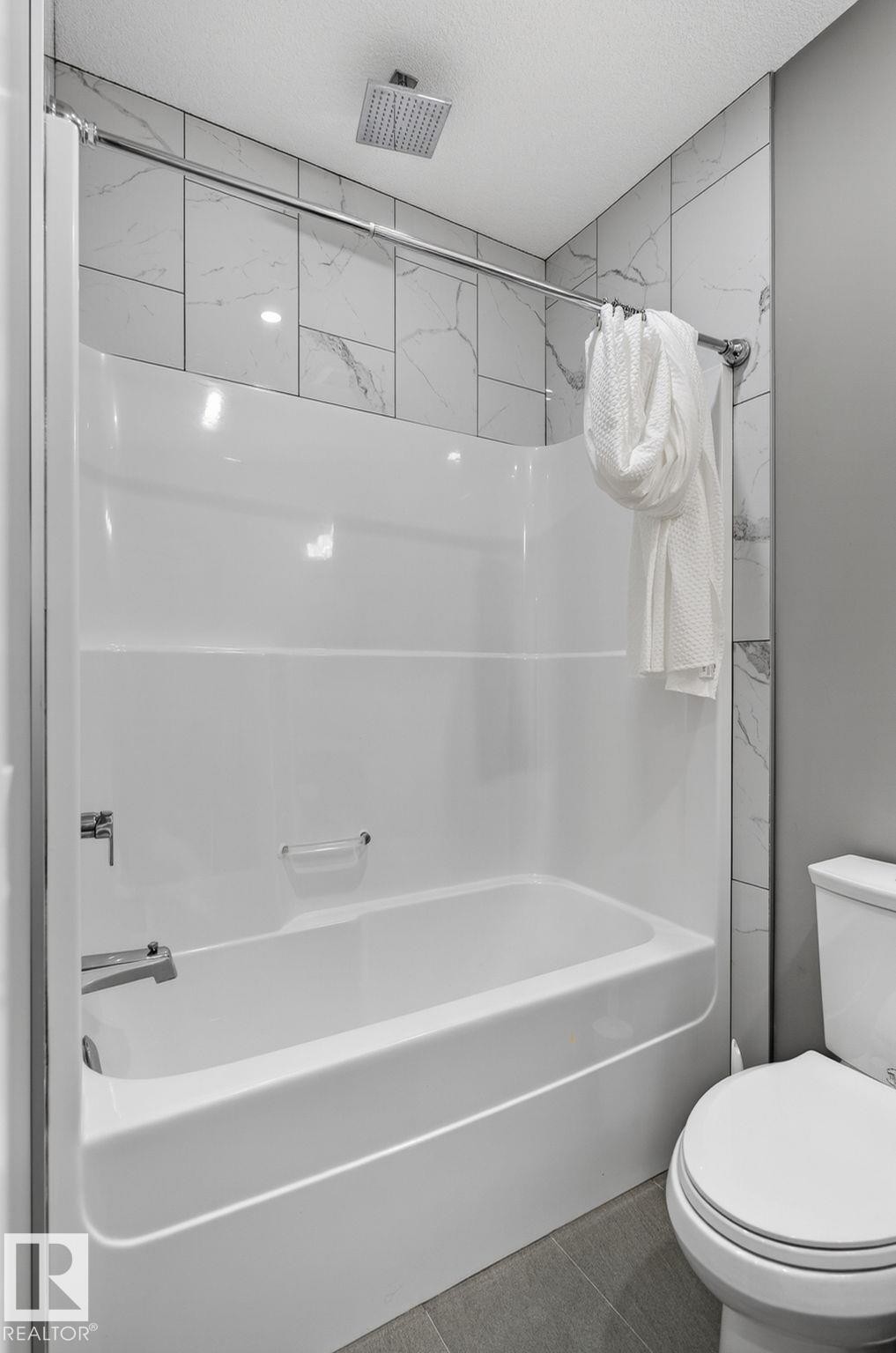 Bathtub-shower combination featuring a white surround and a ceiling-mounted rainfall showerhead - 8809 148 Street, Edmonton, AB - Indoor Photo Showing Bathroom