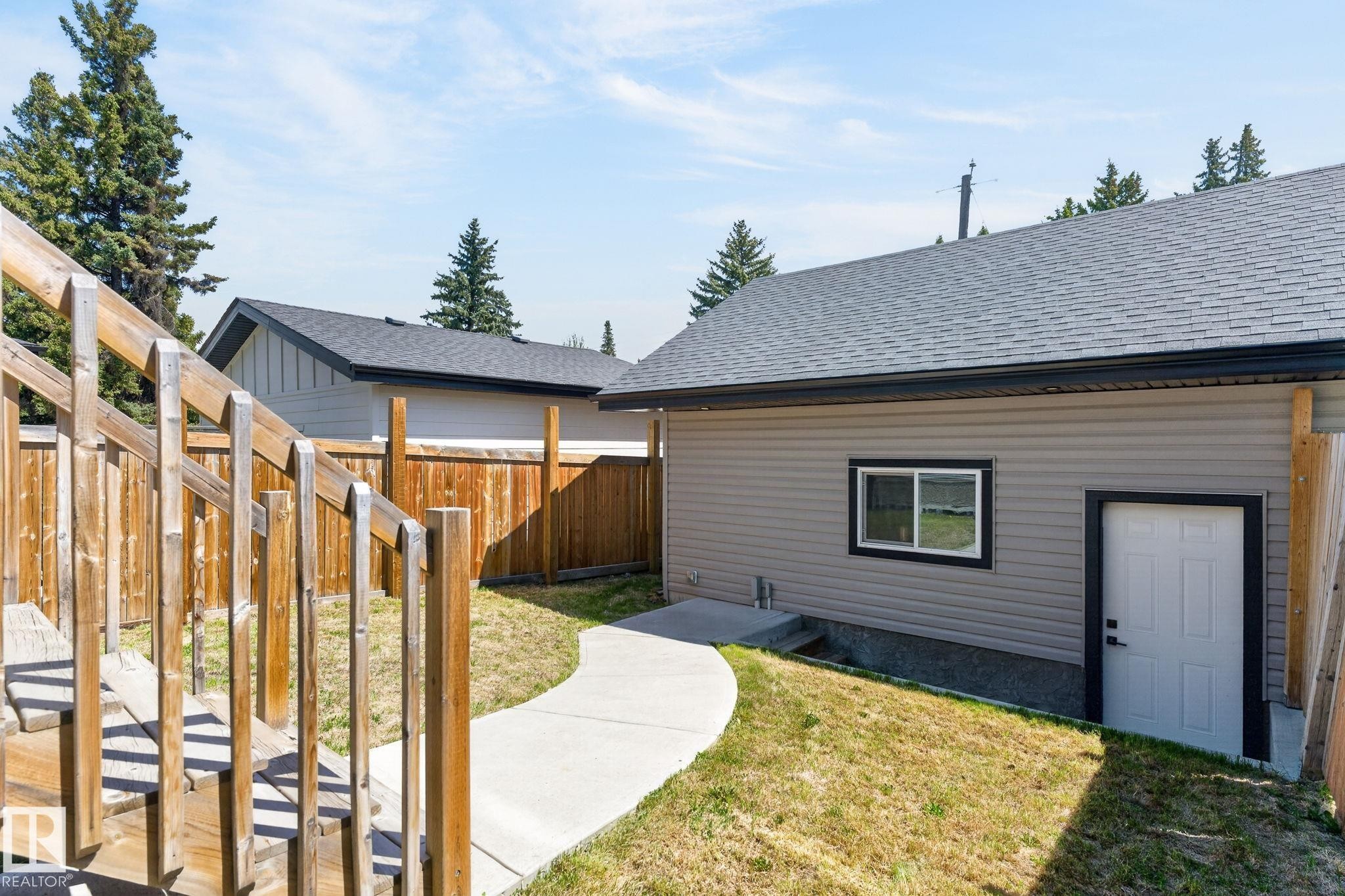 Rear exterior featuring gray siding, a white service door with black trim, and a sliding window - 8809 148 Street, Edmonton, AB - Outdoor With Exterior