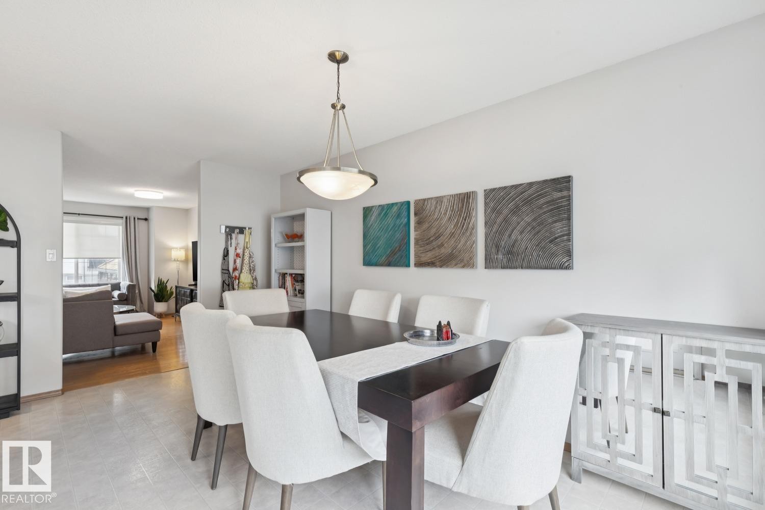 Dining area with overhead fixture, light tile flooring, and a dark wood-finish dining table - 1 225 Blackburn Drive E, Edmonton, AB