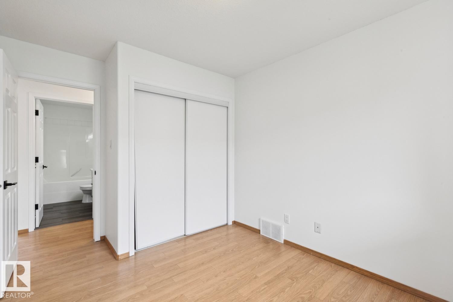 Room featuring light wood-finish flooring, white walls, and a built-in closet with sliding doors - 1 225 Blackburn Drive E, Edmonton, AB
