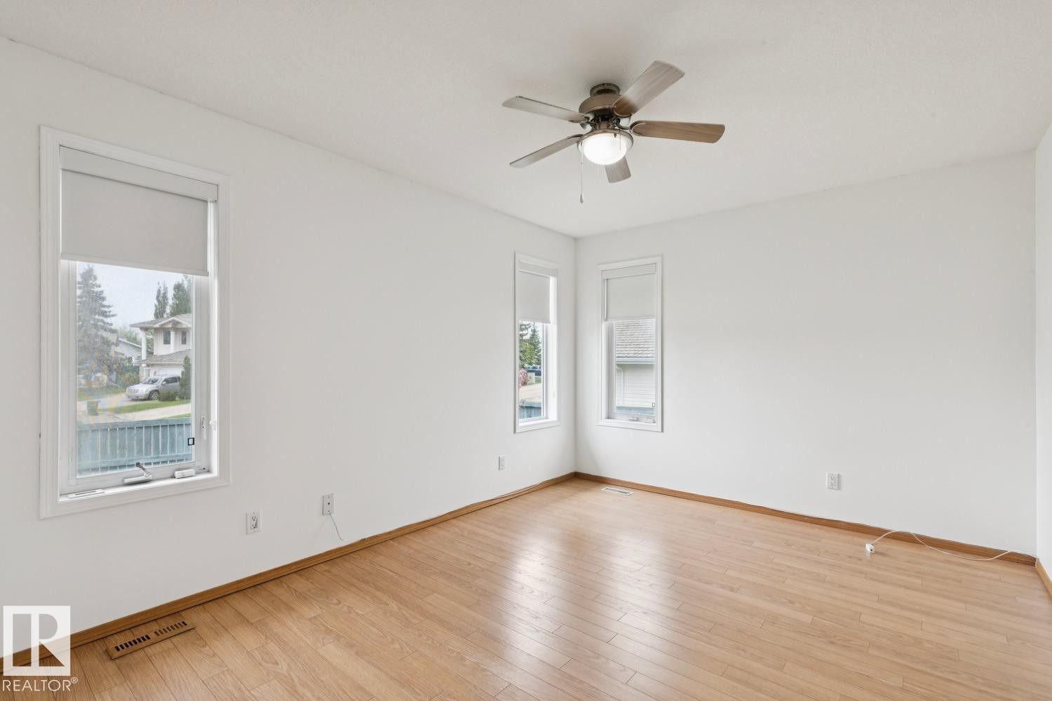 Bright room featuring wood-finish flooring, white walls, and a ceiling fan with integrated lighting - 1 225 Blackburn Drive E, Edmonton, AB