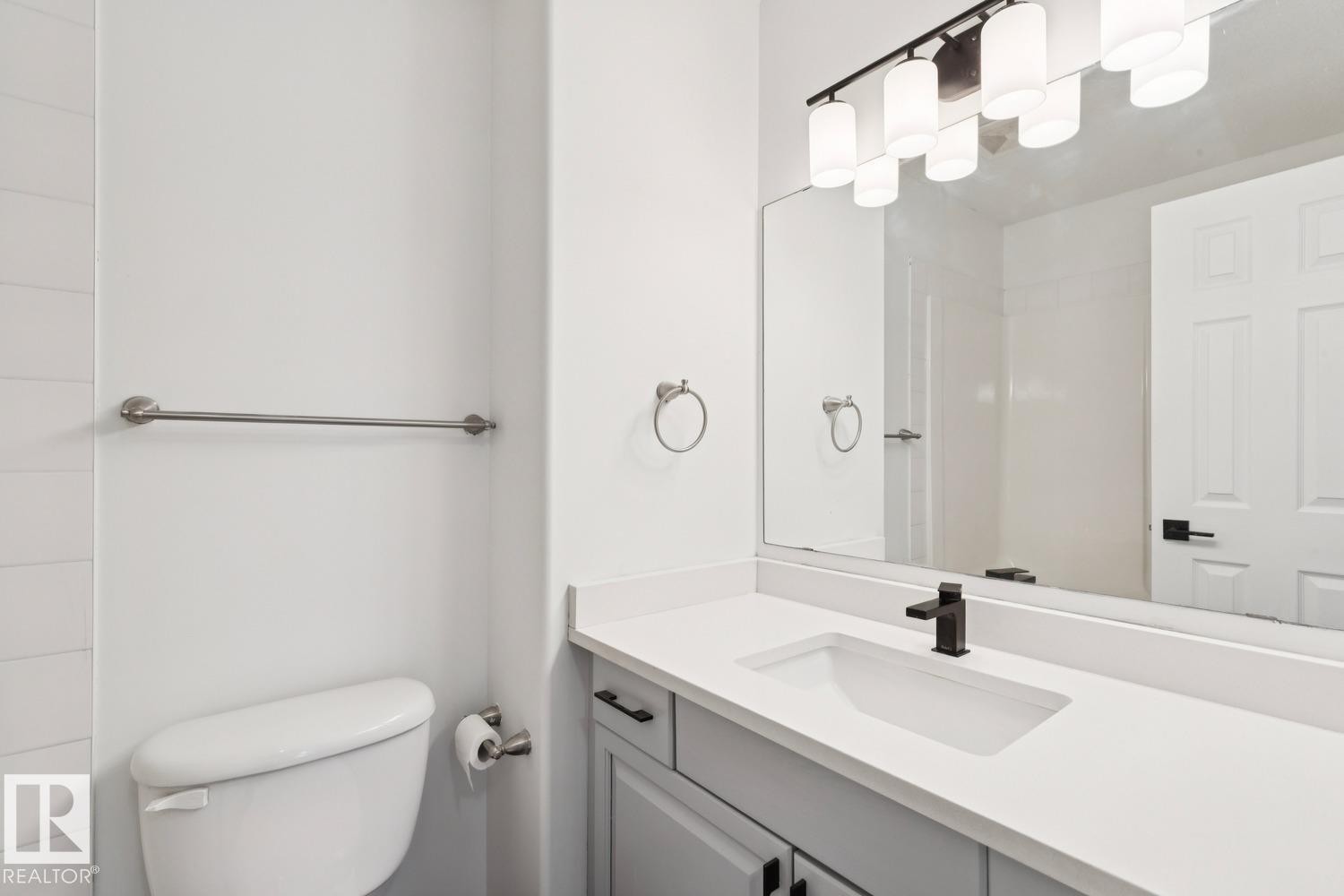 Bathroom vanity featuring a matte black single-handle faucet, integrated rectangular sink, and light-toned countertop - 1 225 Blackburn Drive E, Edmonton, AB
