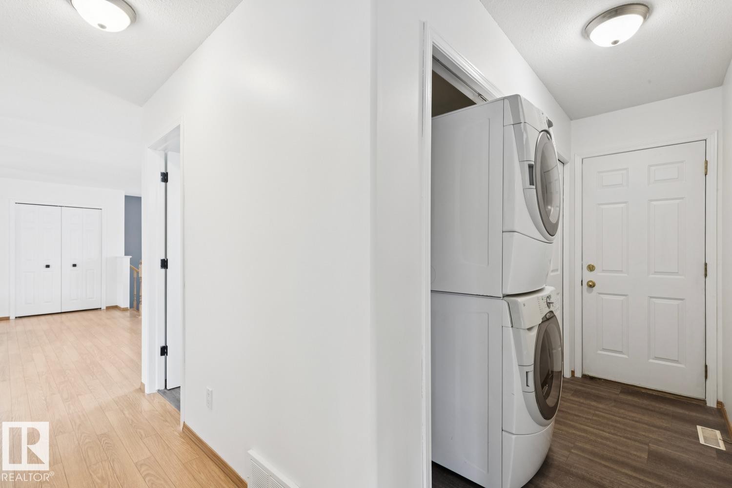 Dedicated laundry area featuring a stacked washer and dryer unit - 1 225 Blackburn Drive E, Edmonton, AB