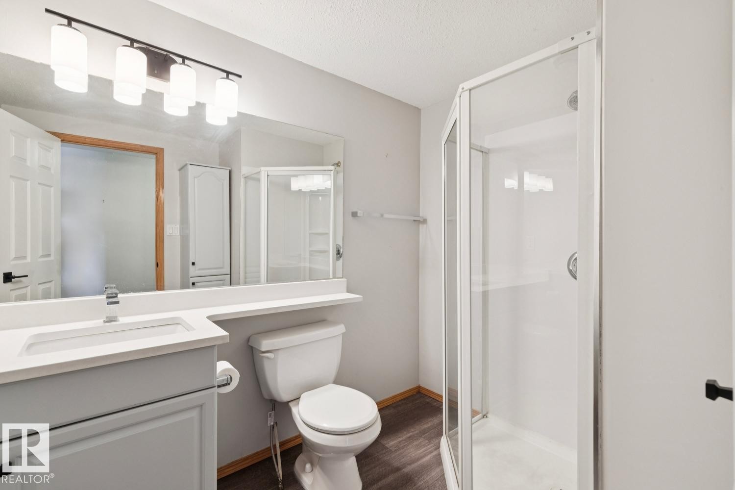Bathroom featuring a white vanity with integrated sink, rectangular mirror, and contemporary four-light fixture - 1 225 Blackburn Drive E, Edmonton, AB