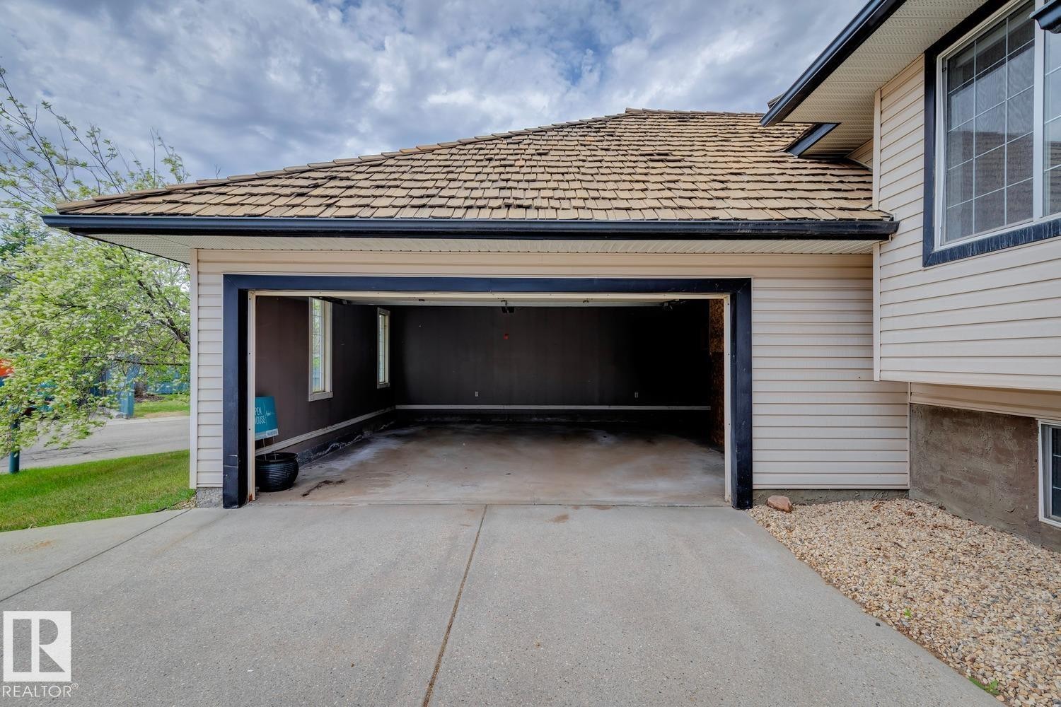 Attached double garage with an unfinished interior, concrete flooring, and windows - 1 225 Blackburn Drive E, Edmonton, AB