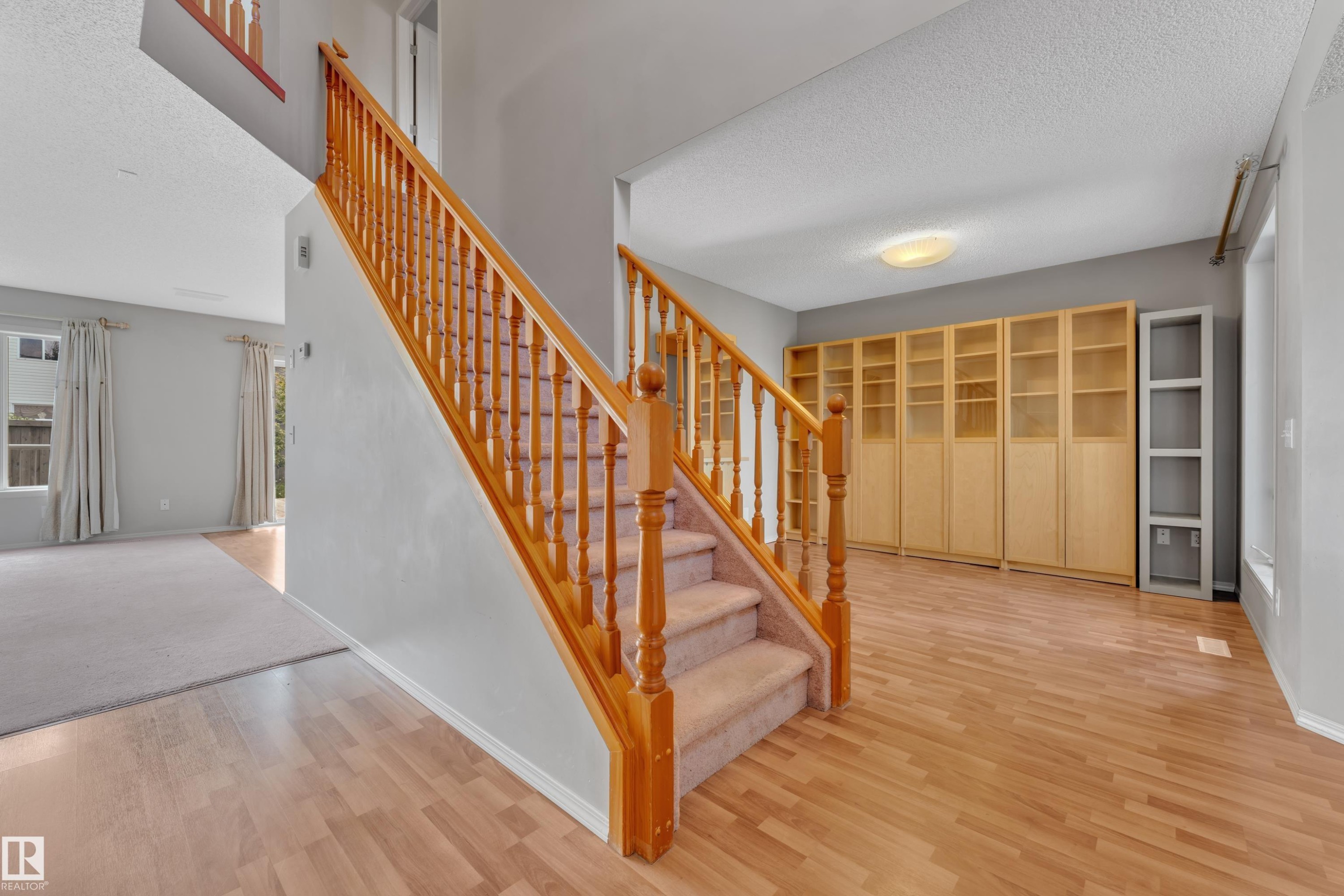 Staircase with wood balusters and carpeted treads, complemented by light wood-finish flooring - 14031 136 Street, Edmonton, AB