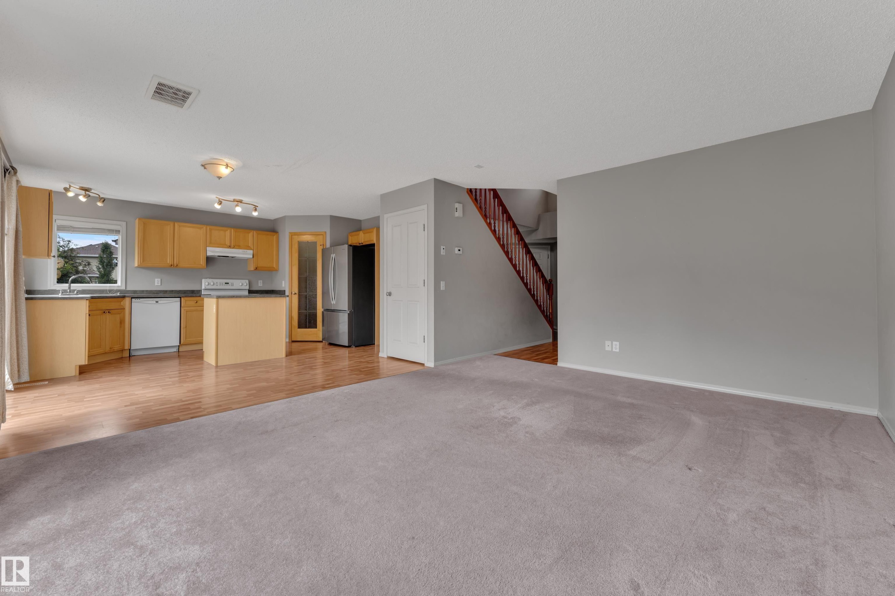 Open-concept living area featuring a kitchen with light wood cabinetry, white appliances, and a central island - 14031 136 Street, Edmonton, AB