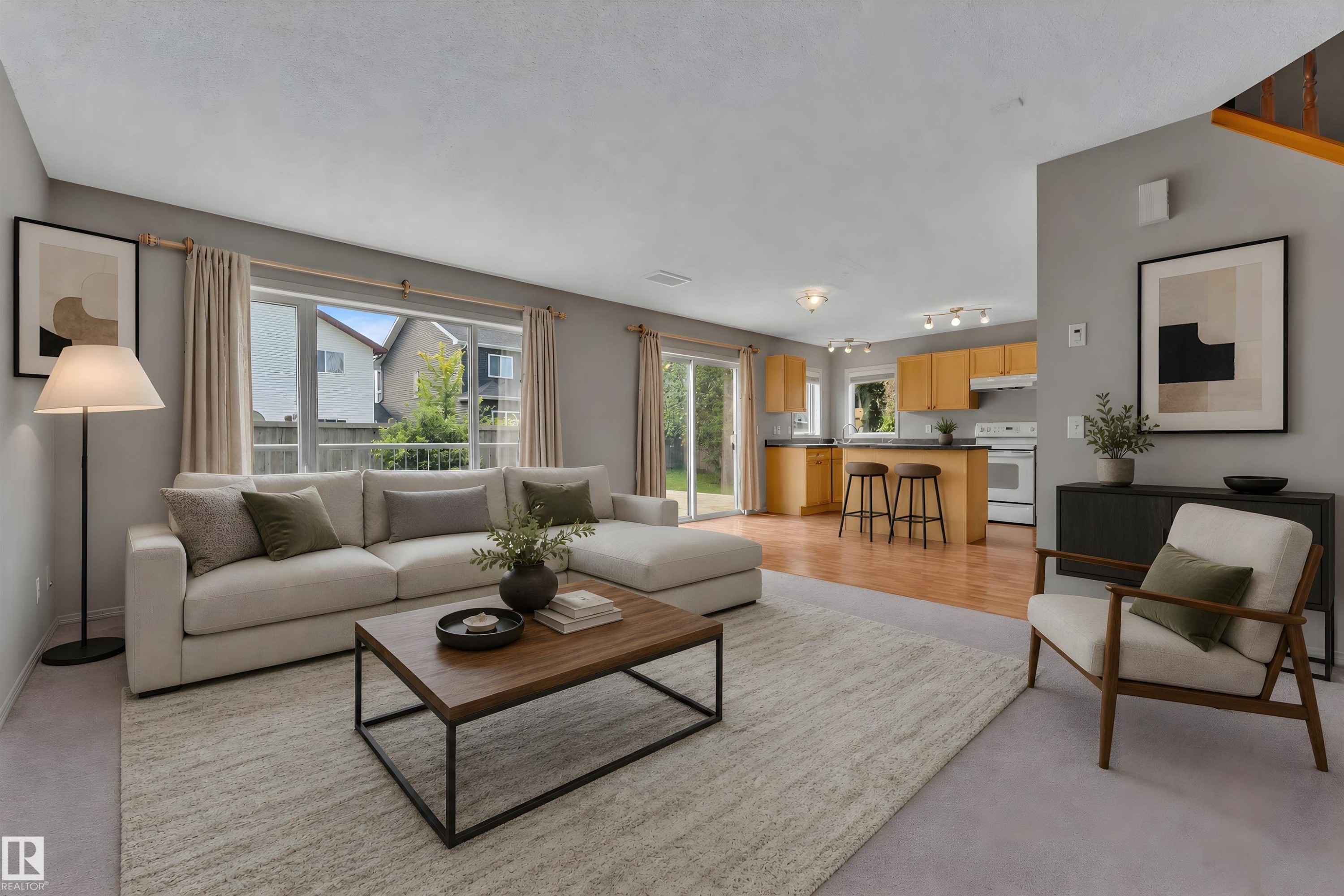 Living area with light gray carpeting and a large window overlooking the backyard - 14031 136 Street, Edmonton, AB