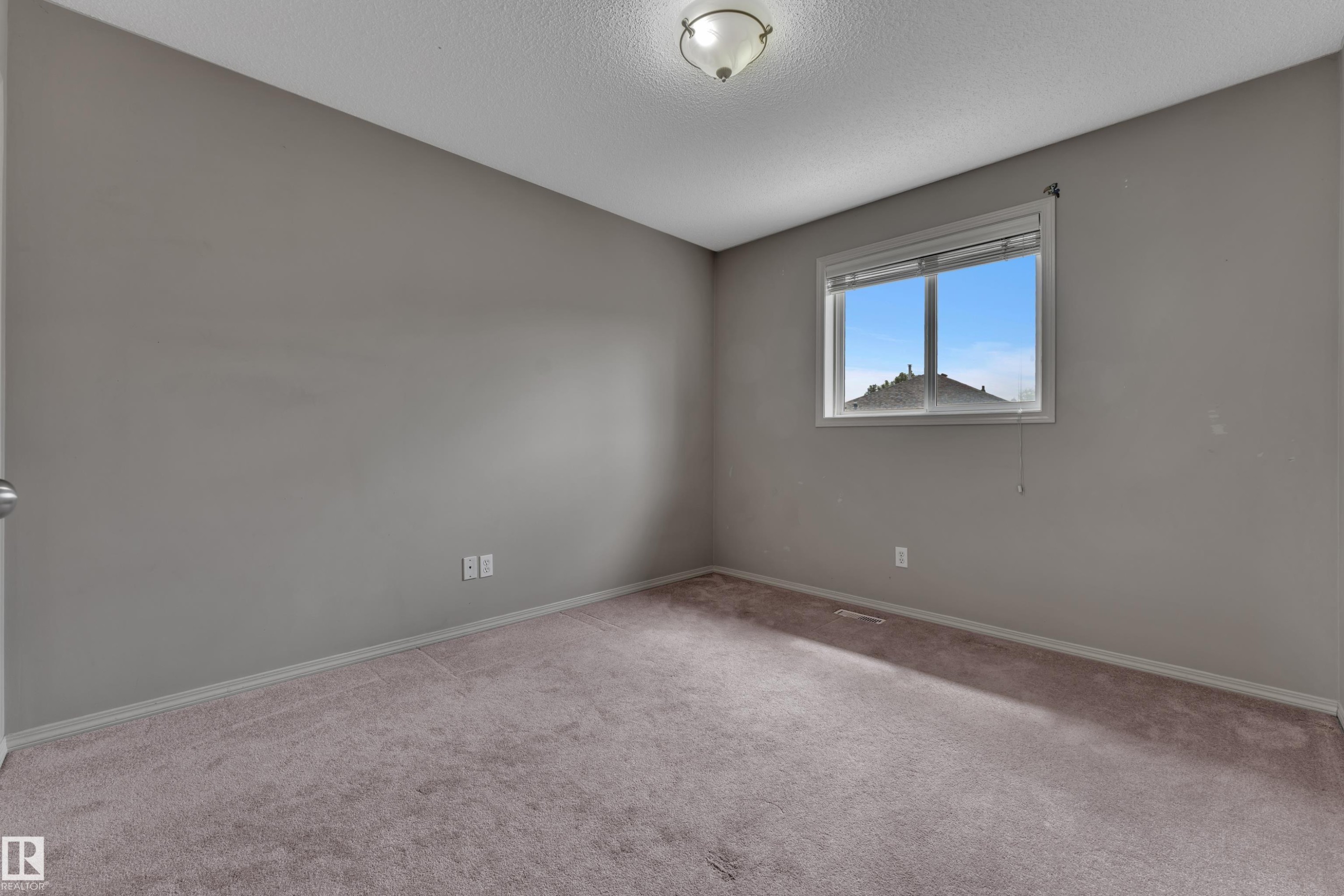 Neutral-toned room featuring a single window, ceiling-mounted light fixture, and wall-to-wall carpeting - 14031 136 Street, Edmonton, AB