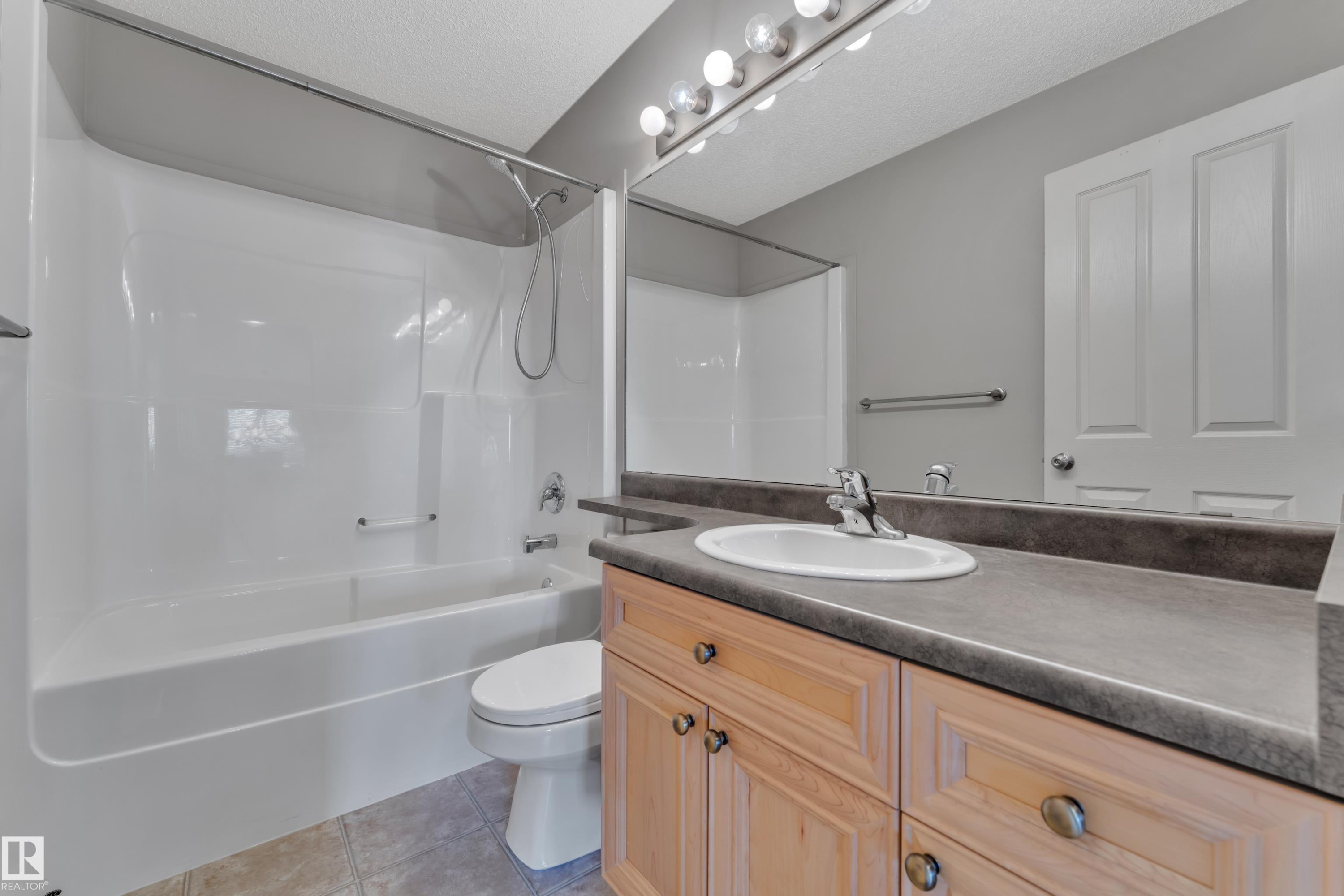 Bathroom featuring a full vanity with wood cabinetry, a built-in sink, and a large mirror with overhead lighting - 14031 136 Street, Edmonton, AB