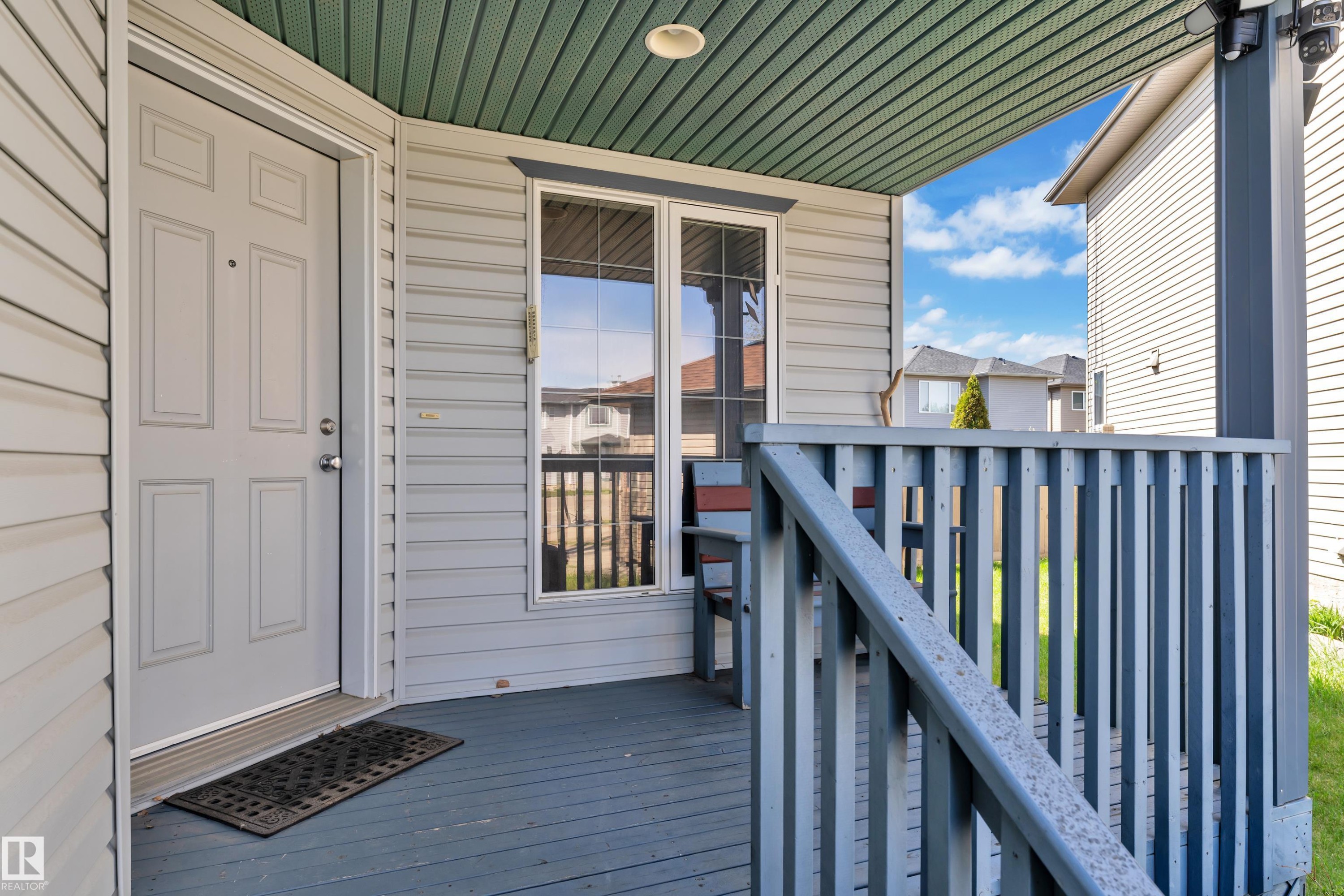Covered front porch featuring a paneled entry door, siding exterior, and a protective railing system - 14031 136 Street, Edmonton, AB