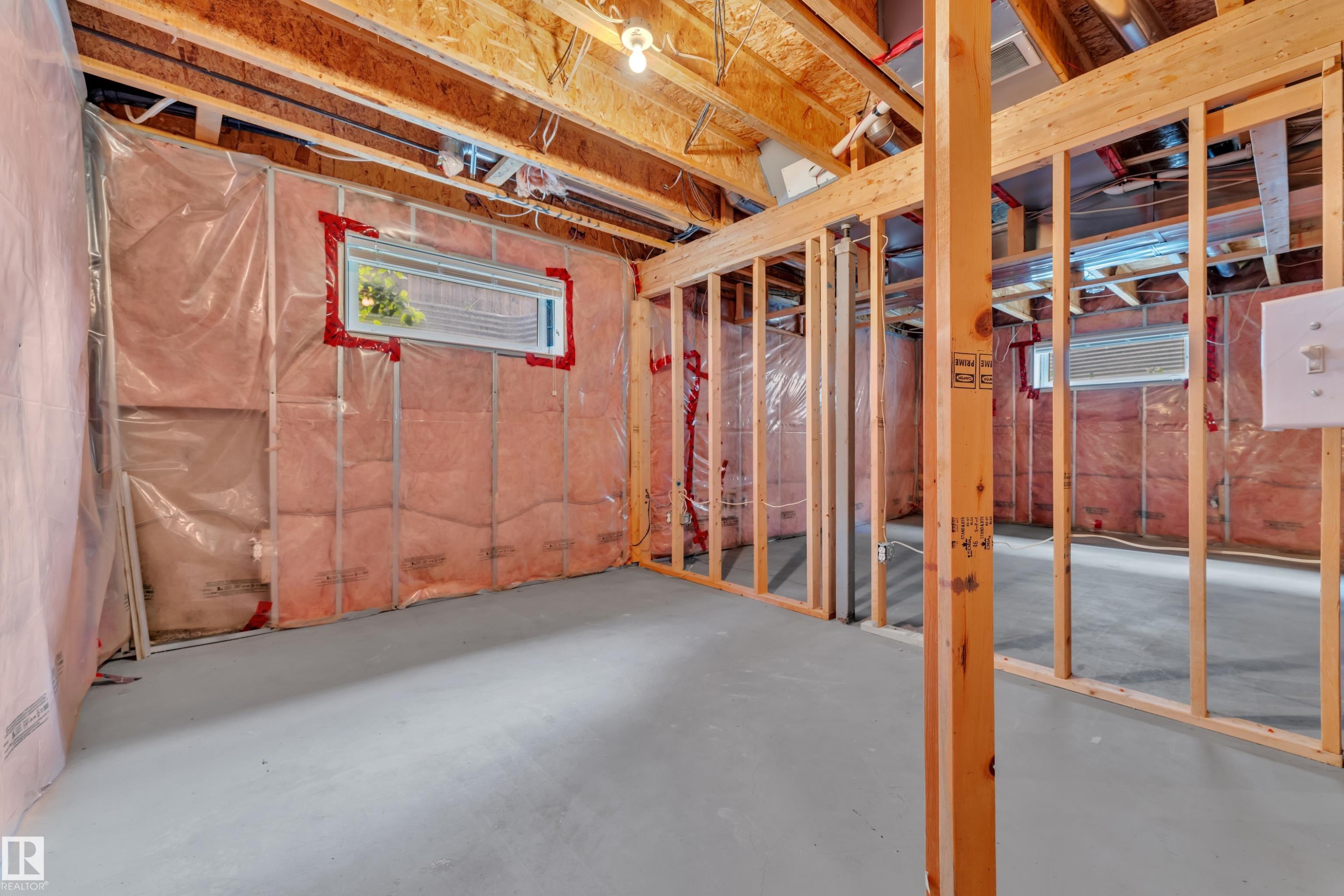 Unfinished basement featuring exposed wood framing, concrete flooring, insulated walls, and two horizontal windows - 14031 136 Street, Edmonton, AB