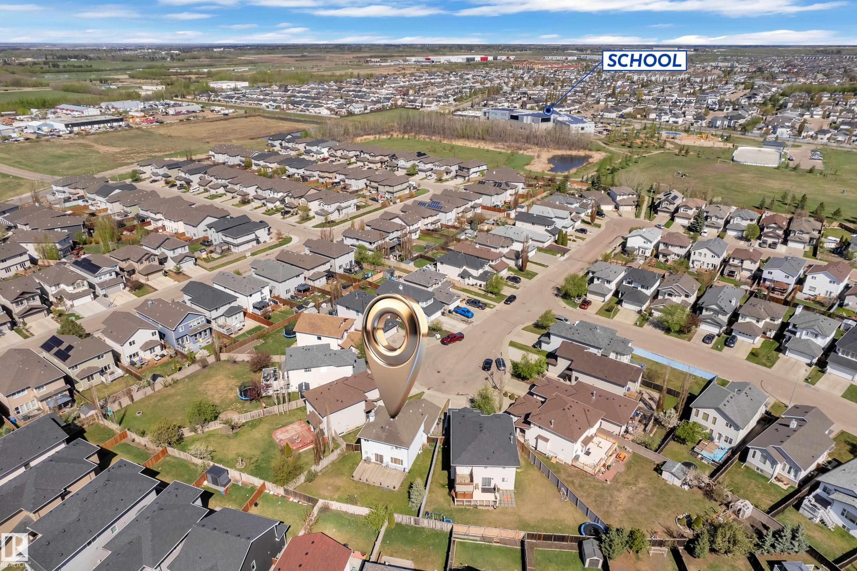 Aerial perspective showcasing a residential neighborhood with a prominent school building in the background - 14031 136 Street, Edmonton, AB