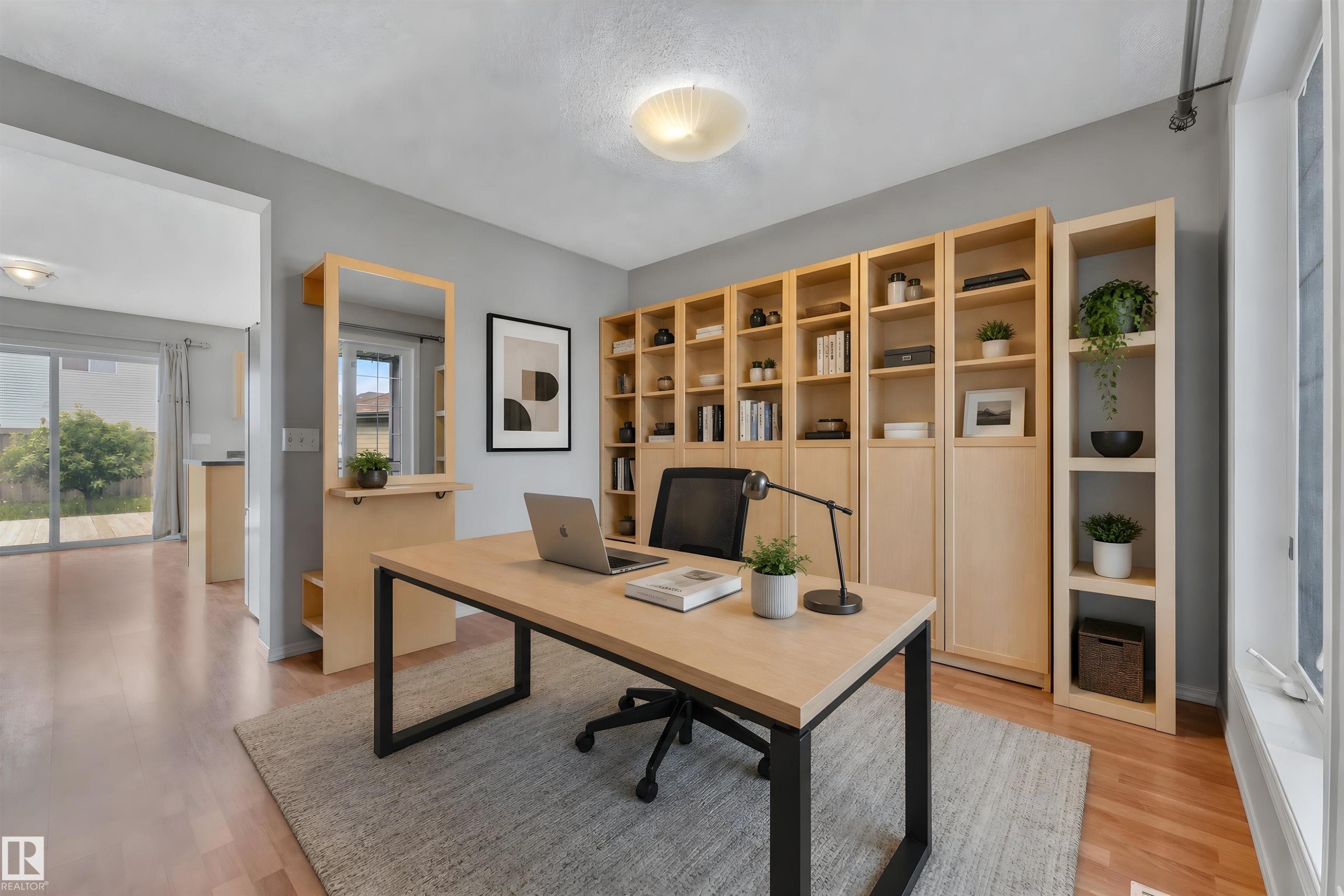 Dedicated office space featuring extensive built-in shelving, wood-finish flooring, and a contemporary light fixture - 14031 136 Street, Edmonton, AB