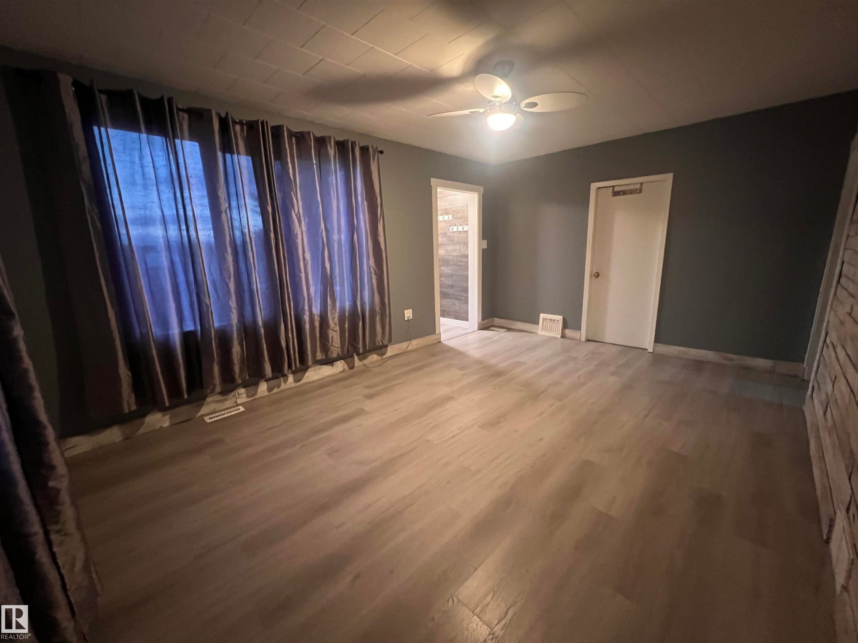 Spacious interior room featuring wood-finish flooring, a ceiling fan, and dark-toned walls - 69 Railway Avenue, Star, AB