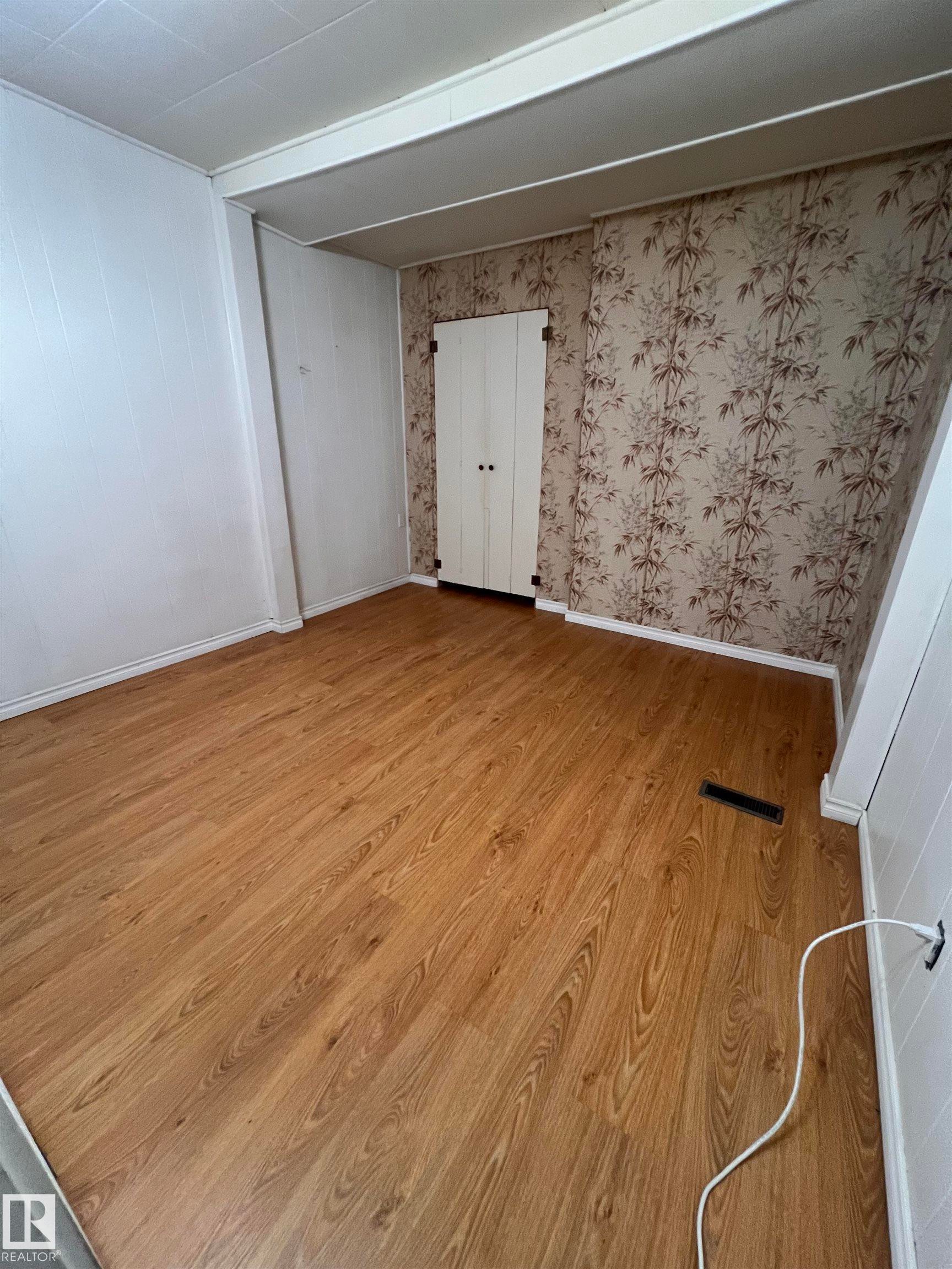 Room featuring wood-finish flooring, two-tone wall finishes, and a built-in wardrobe with white paneled doors - 69 Railway Avenue, Star, AB