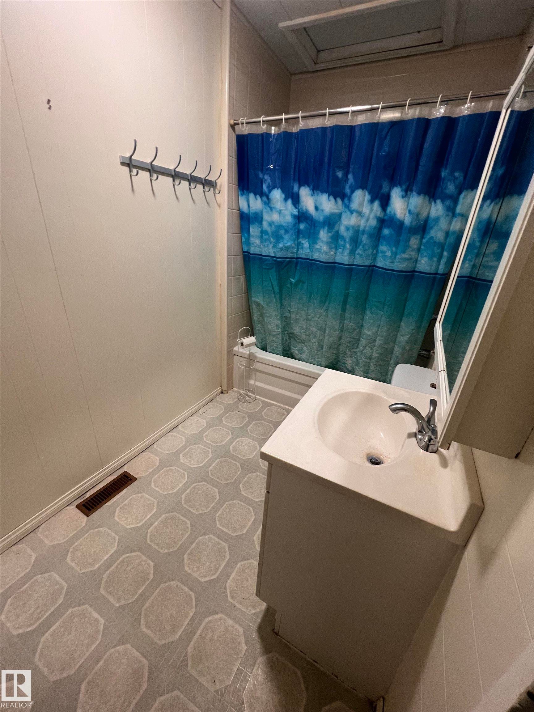 Bathroom featuring a white vanity with integrated sink, chrome faucet, and patterned floor - 69 Railway Avenue, Star, AB
