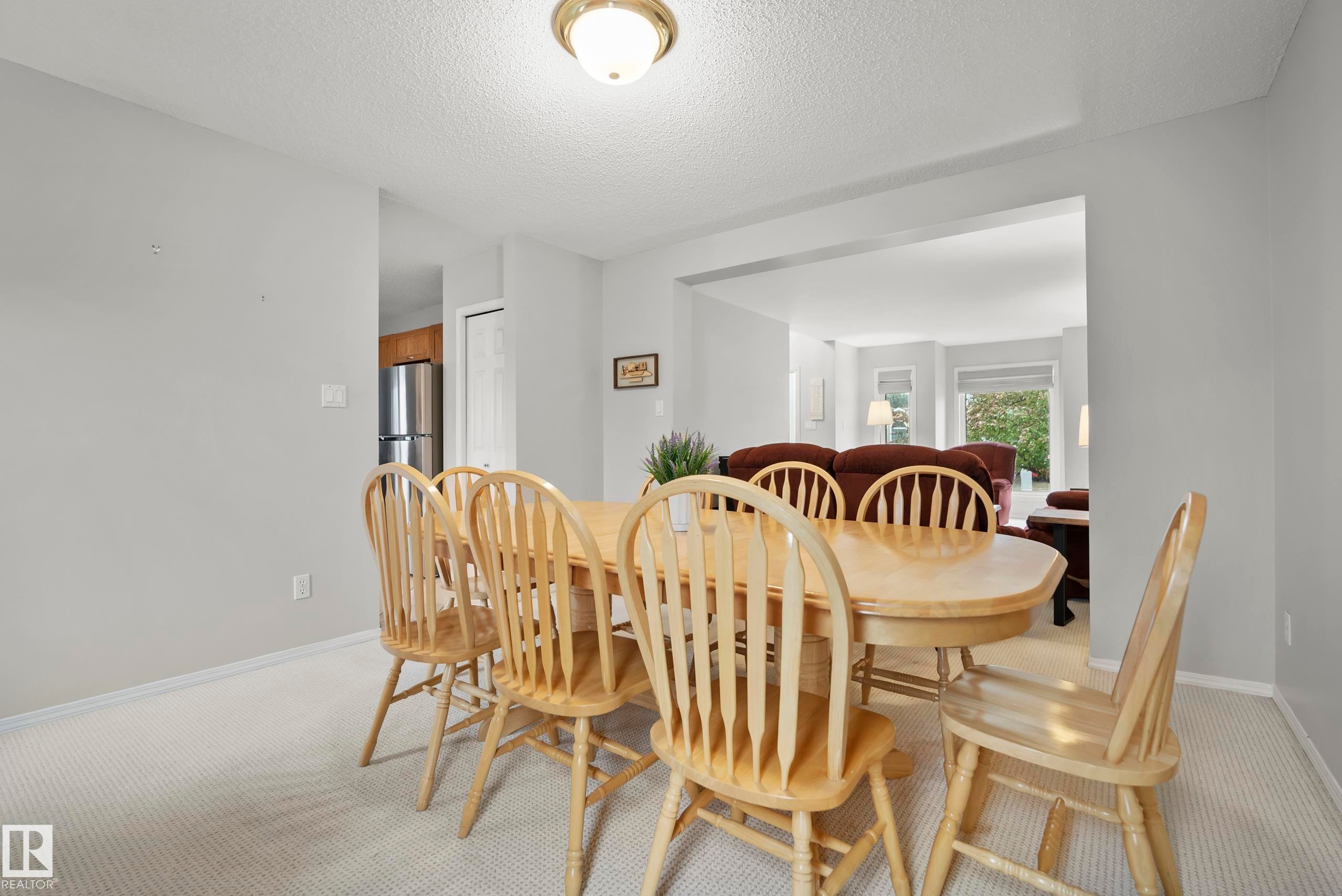 Dining area featuring light gray wall paint, textured carpet flooring, and a flush-mount ceiling light fixture - 15503 62 Street, Edmonton, AB