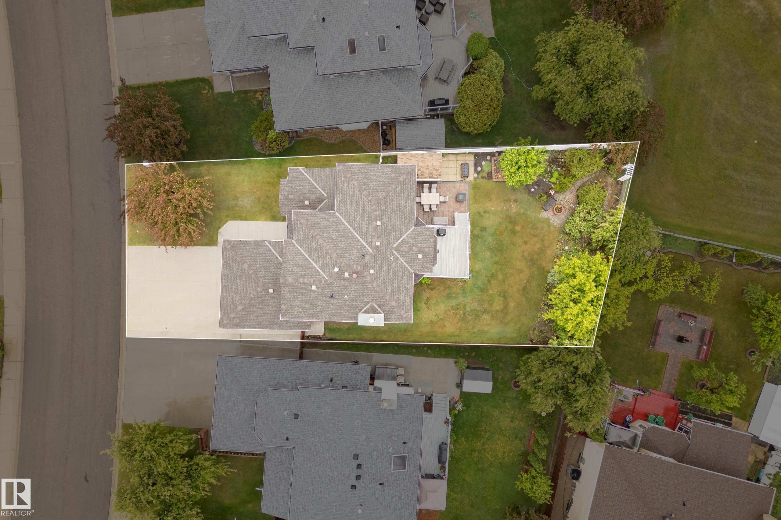 Spacious property featuring a large backyard with a lawn, mature landscaping, and a patio area - 15503 62 Street, Edmonton, AB