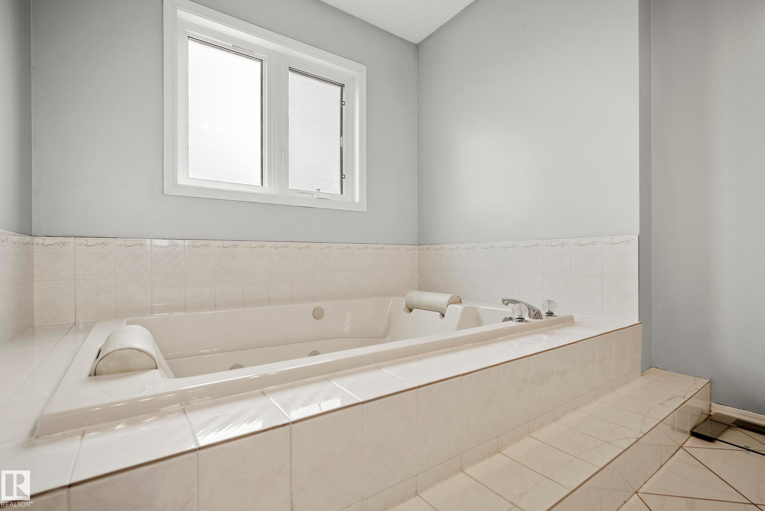 Built-in jetted tub with chrome fixtures, surrounded by white ceramic tile - 15503 62 Street, Edmonton, AB